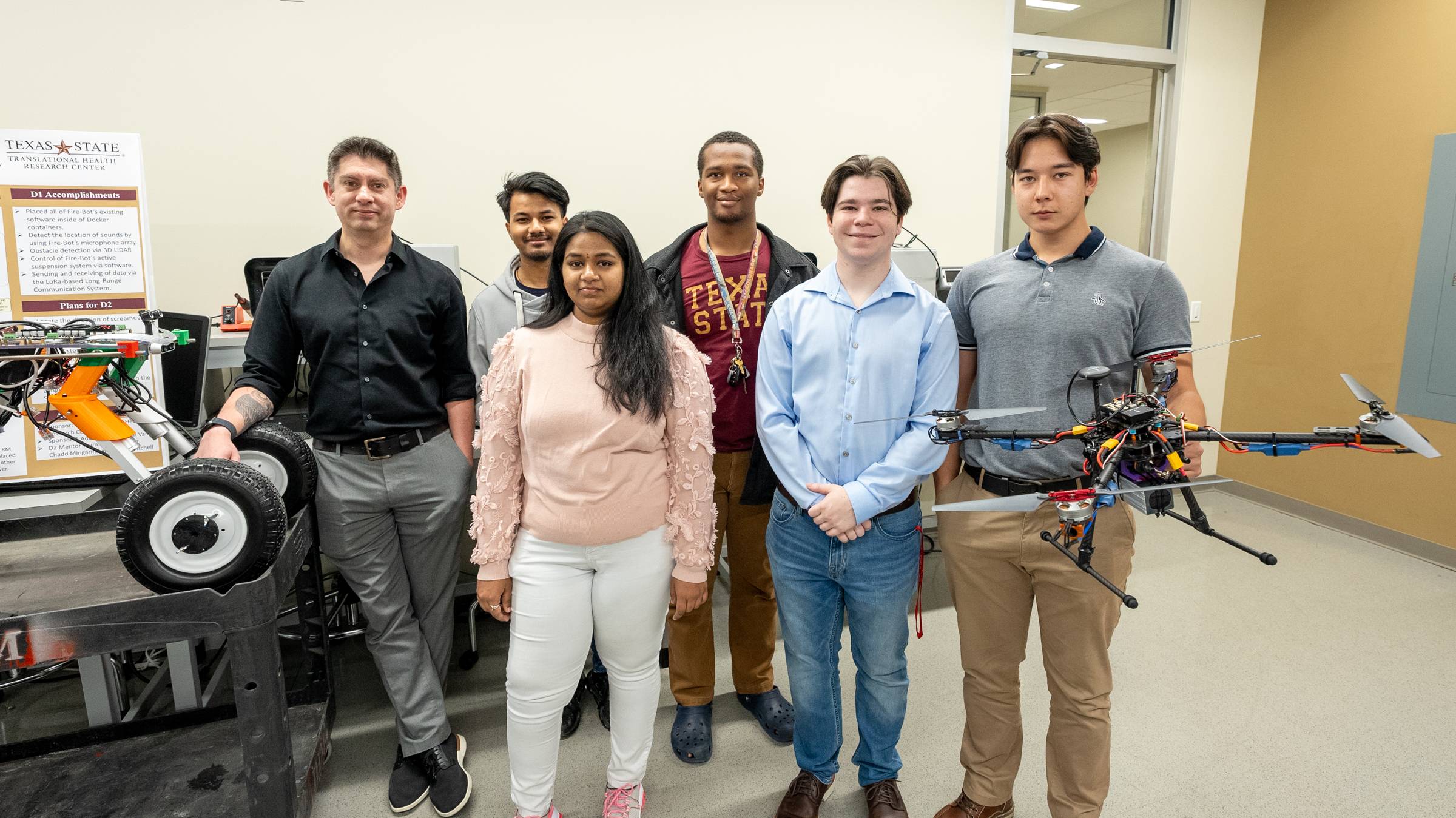 Engineering professor and senior engineering students pose with their engineered drone and rover.