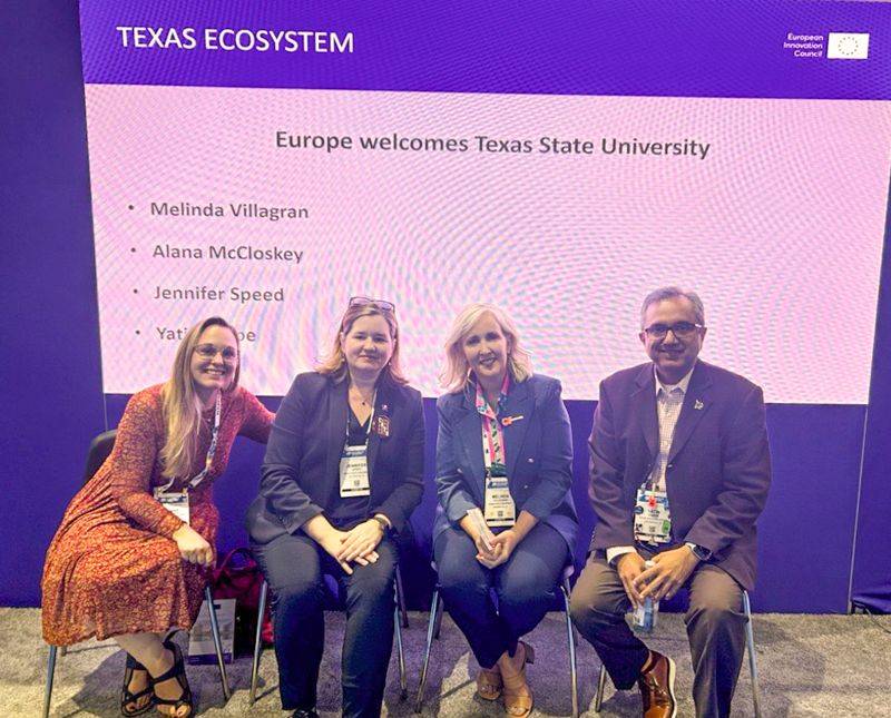 THRC and TXST Bio International Convention Team sit at the front of a panel they presented at.