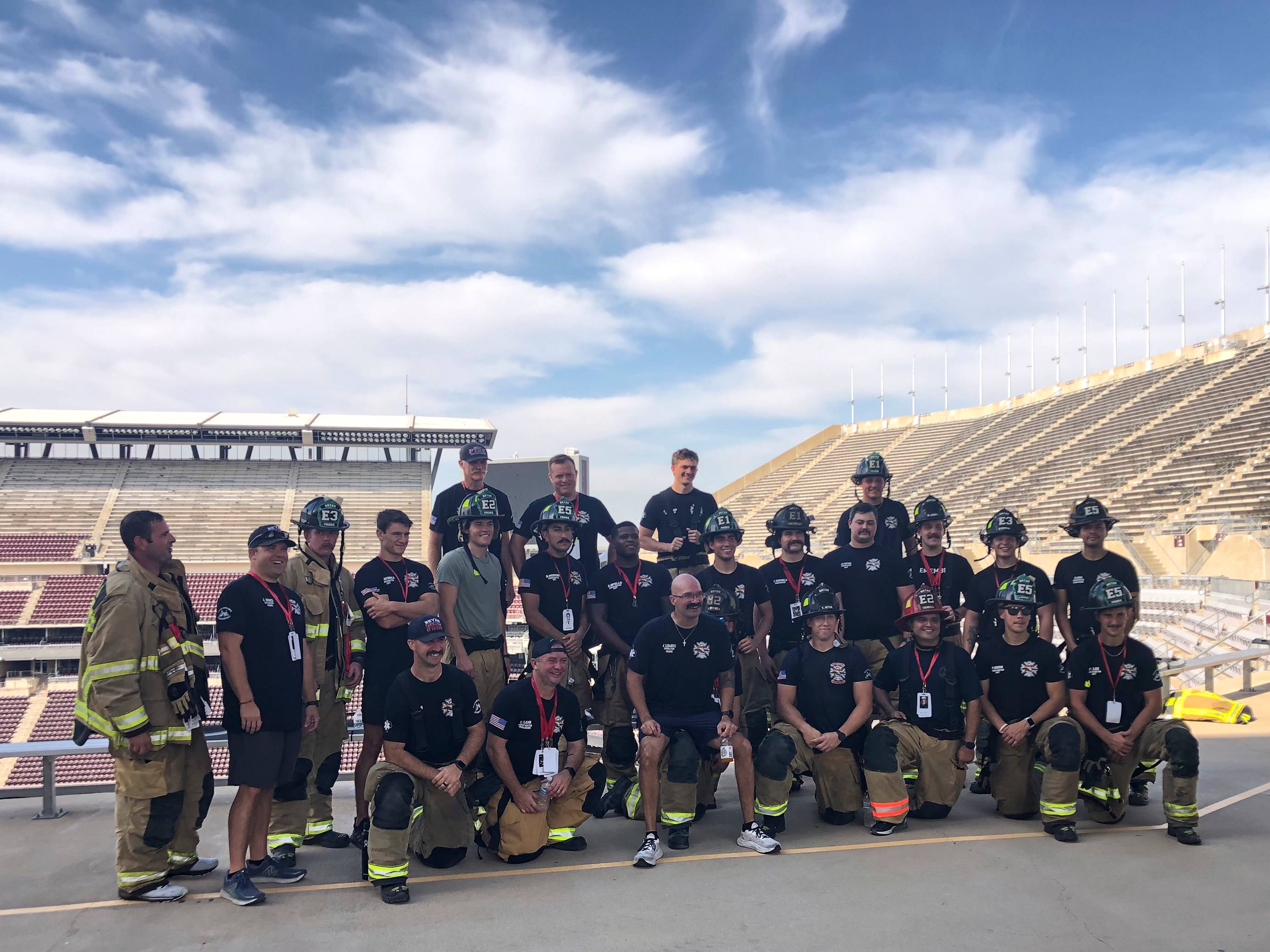 Group of firefighters posing together at the top of arena stairs. 