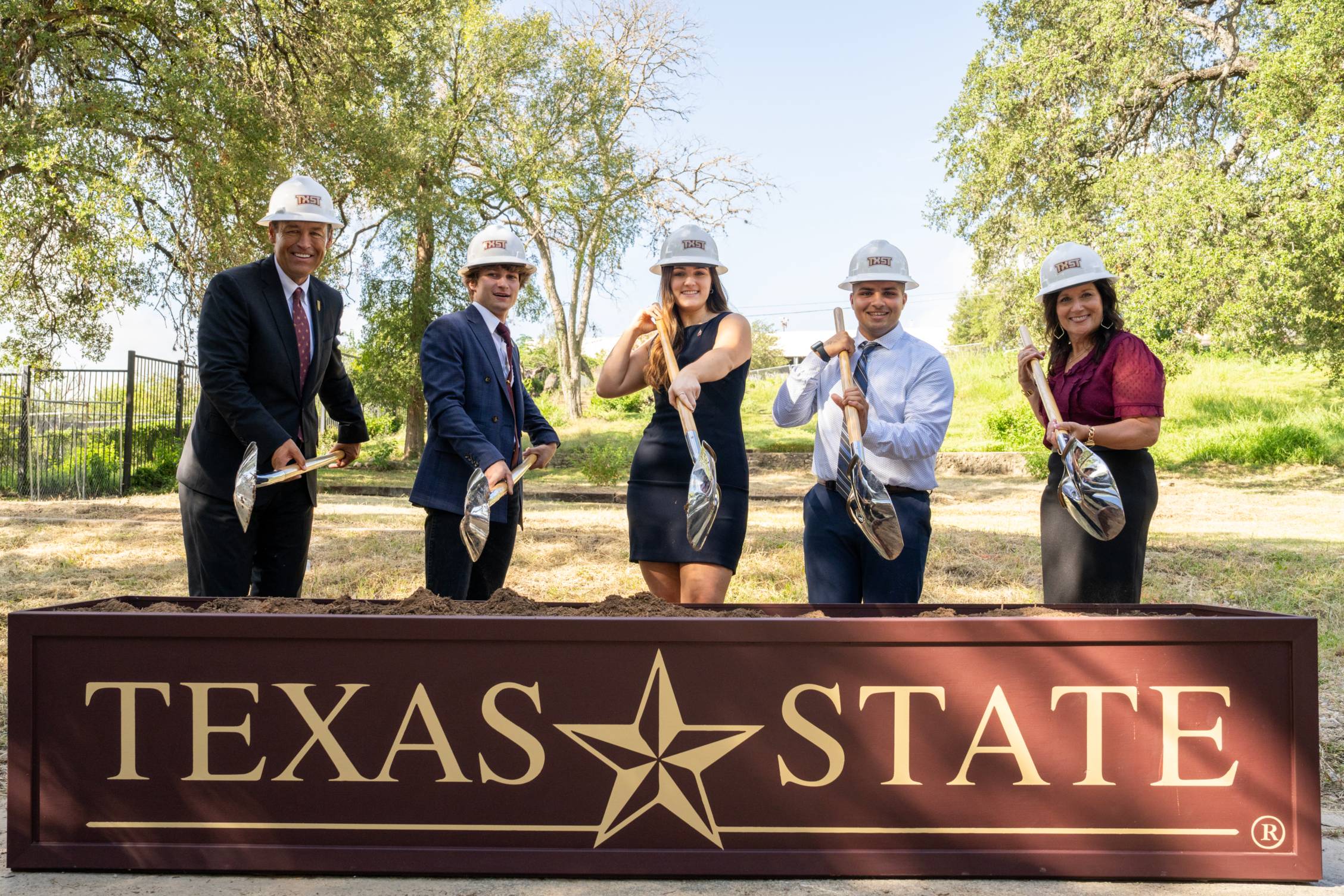 Five people with hard hats and shovels
