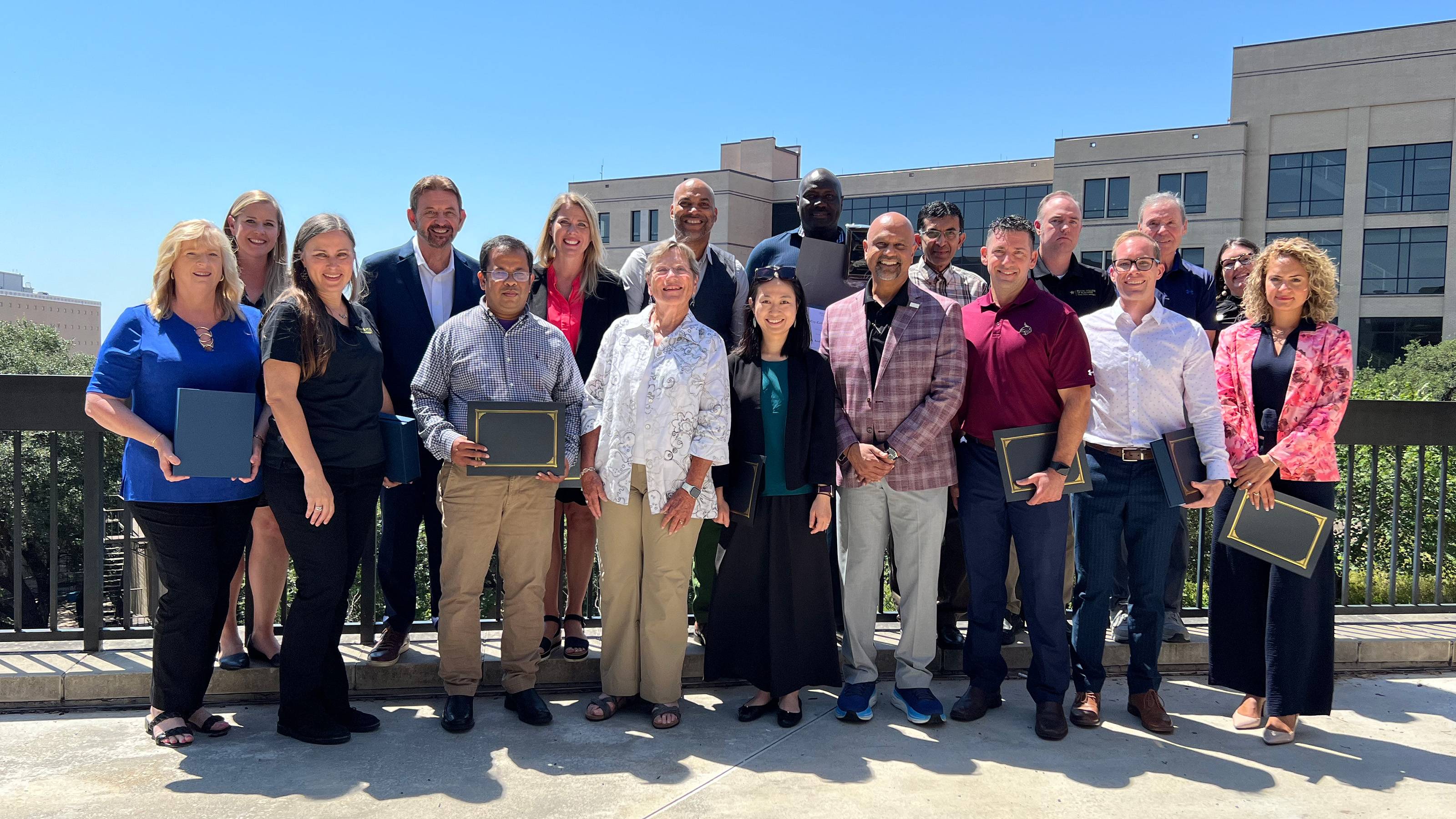 Eighteen award-winning individuals posing together outside