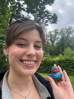 close-up of woman's face, hand, blue rubber duck with "TXST LIBERAL ARTS" printed on it