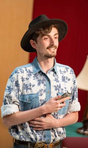 man wearing cowboy hat, button-up shirt, holding iPhone