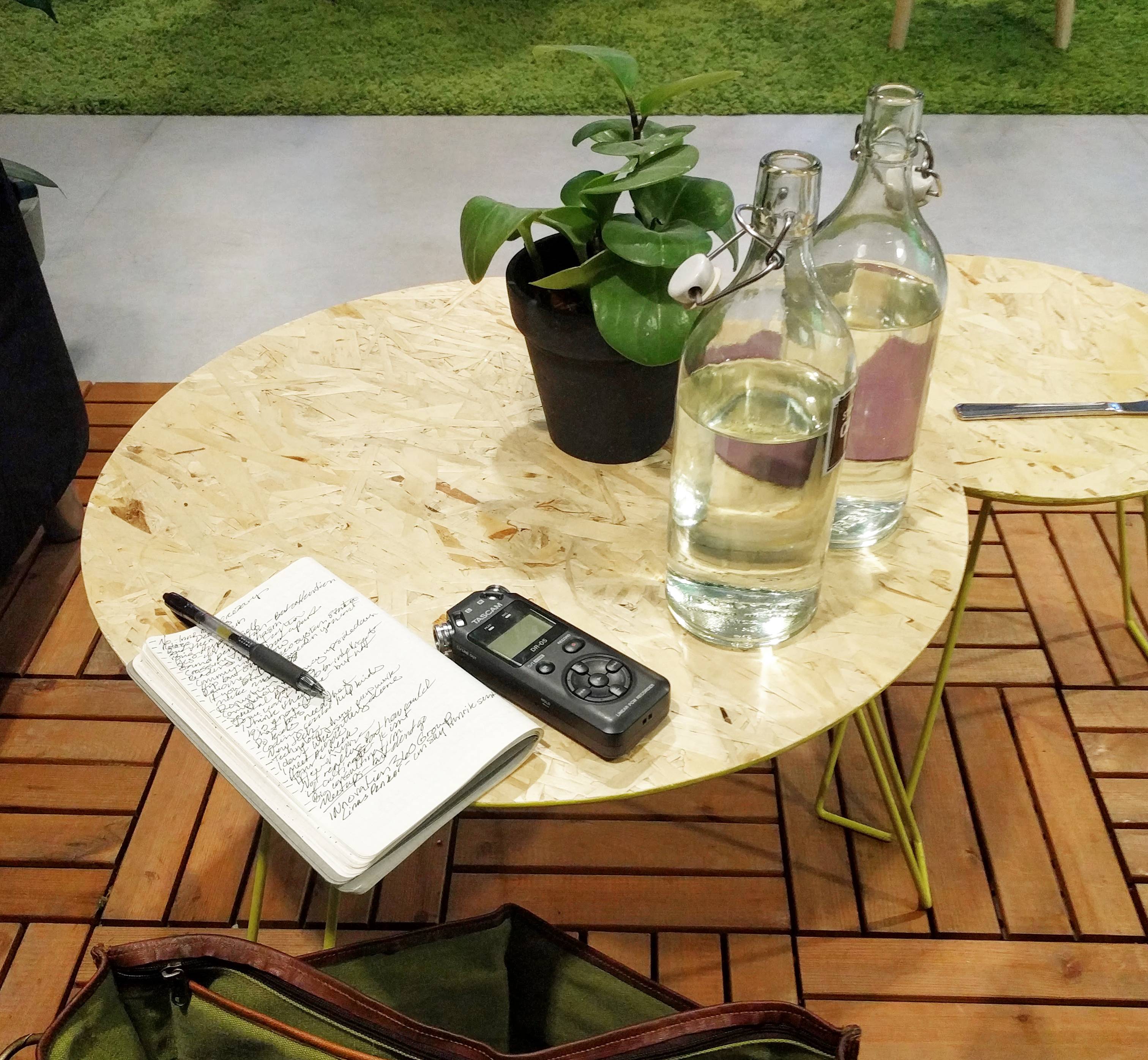 A fieldnotes book and digital audio recorder on a table in a cafe.