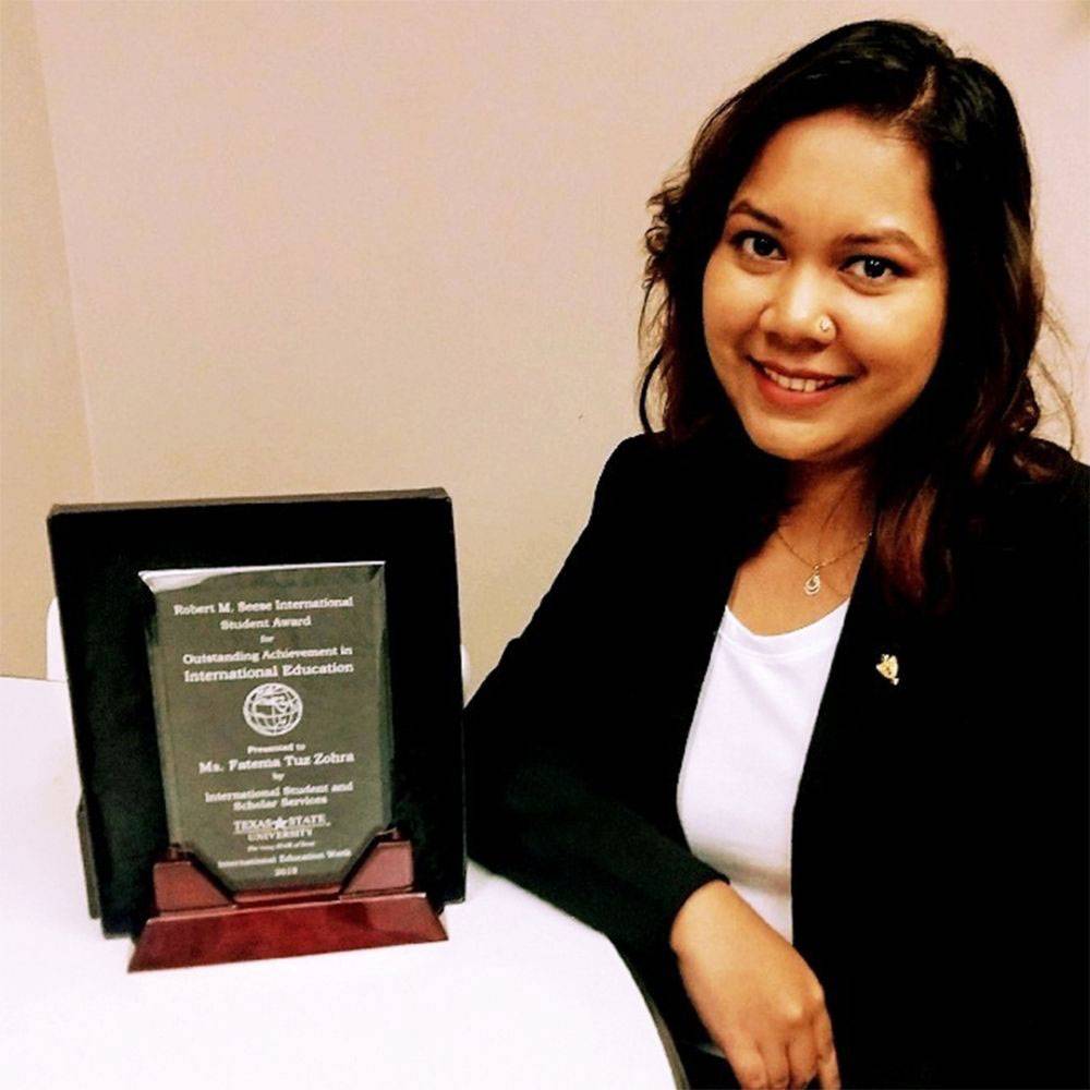 Headshot of Fatema Tuz Zohra holding an award plaque next to her