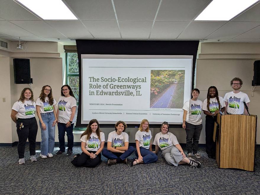 A group of students pose for a photo as they present their research findings.