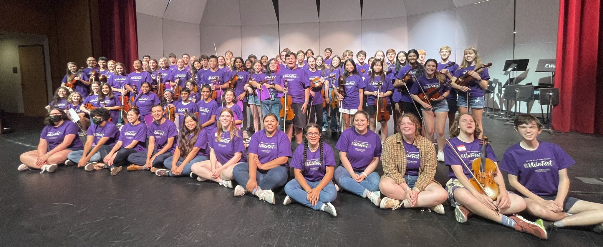 A large group of smiling Texas State ViolaFest participants wearing purple t-shirts.