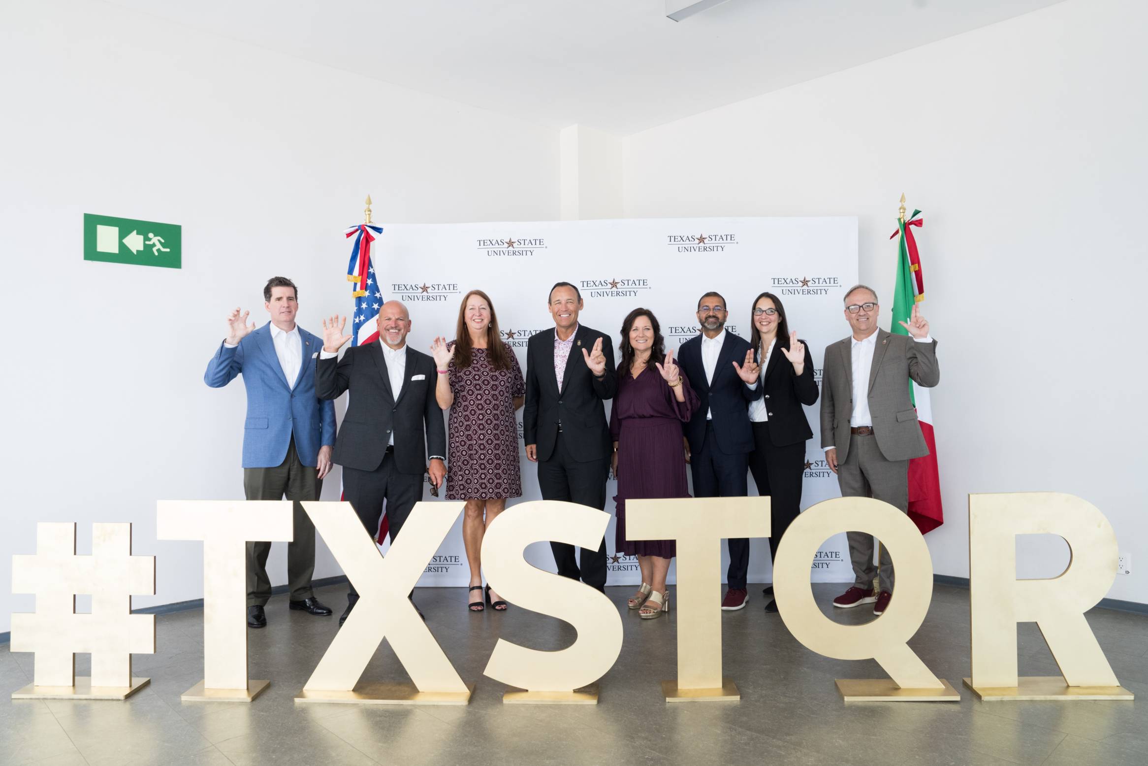 people standing behind a txstqr sign