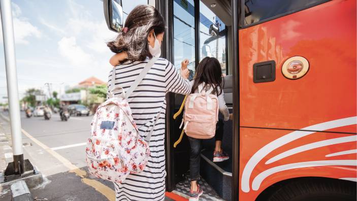 Children wearing masks board a school bus.