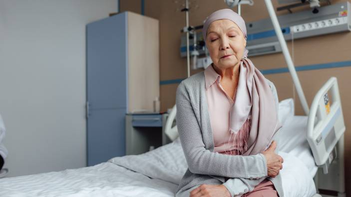 An elderly woman sitting on a hospital bed.