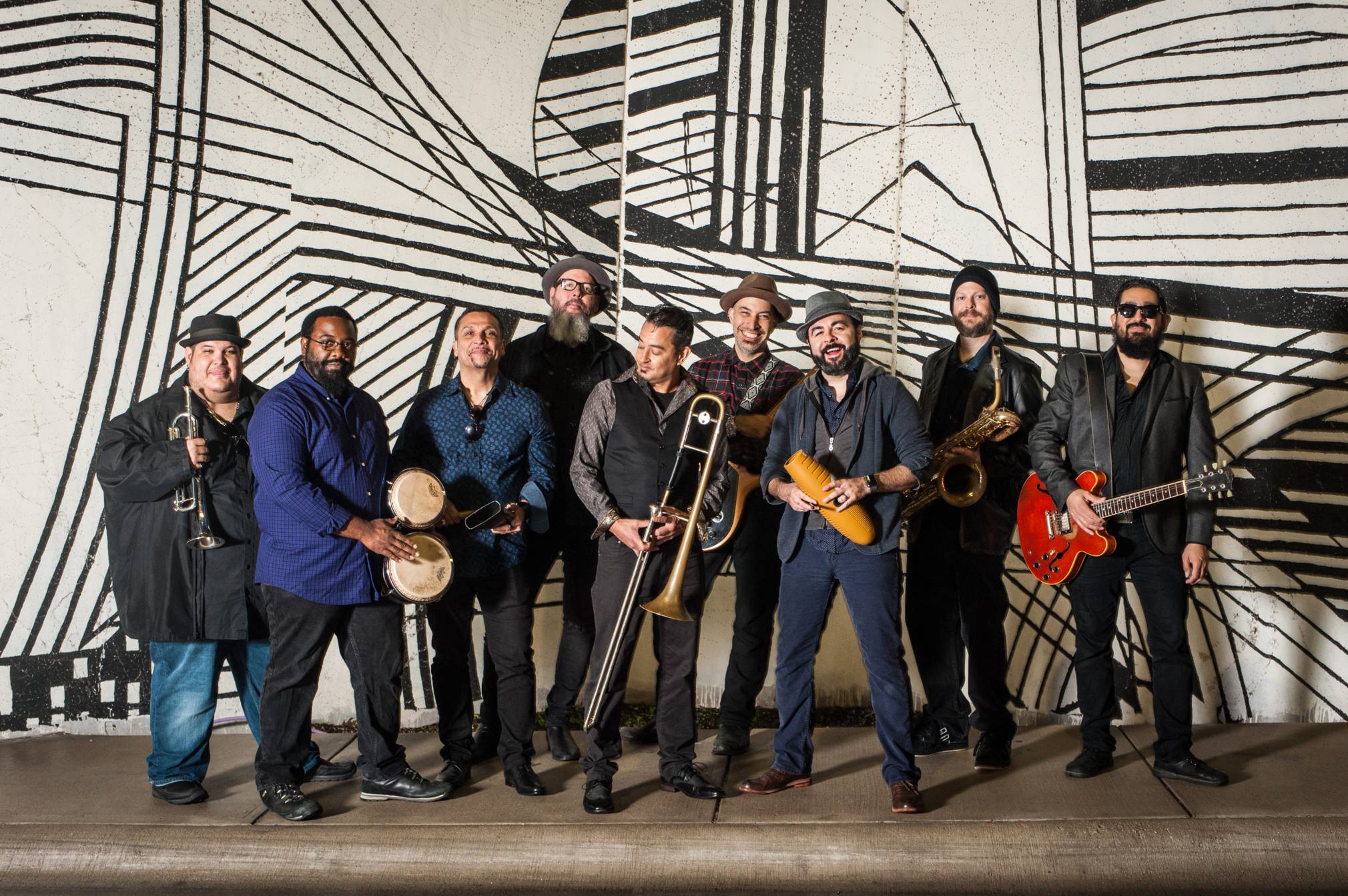 Image of nine men posing together with various instruments.