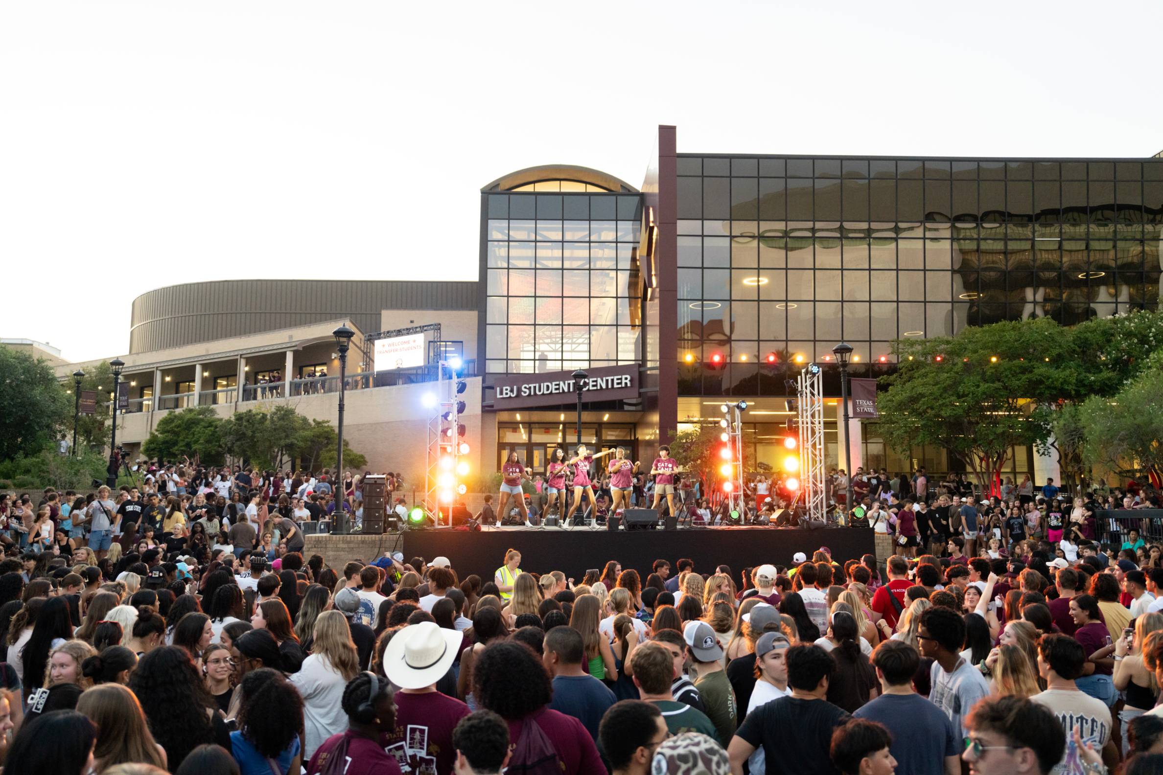 large crowd of people surrounding a large stage on campus