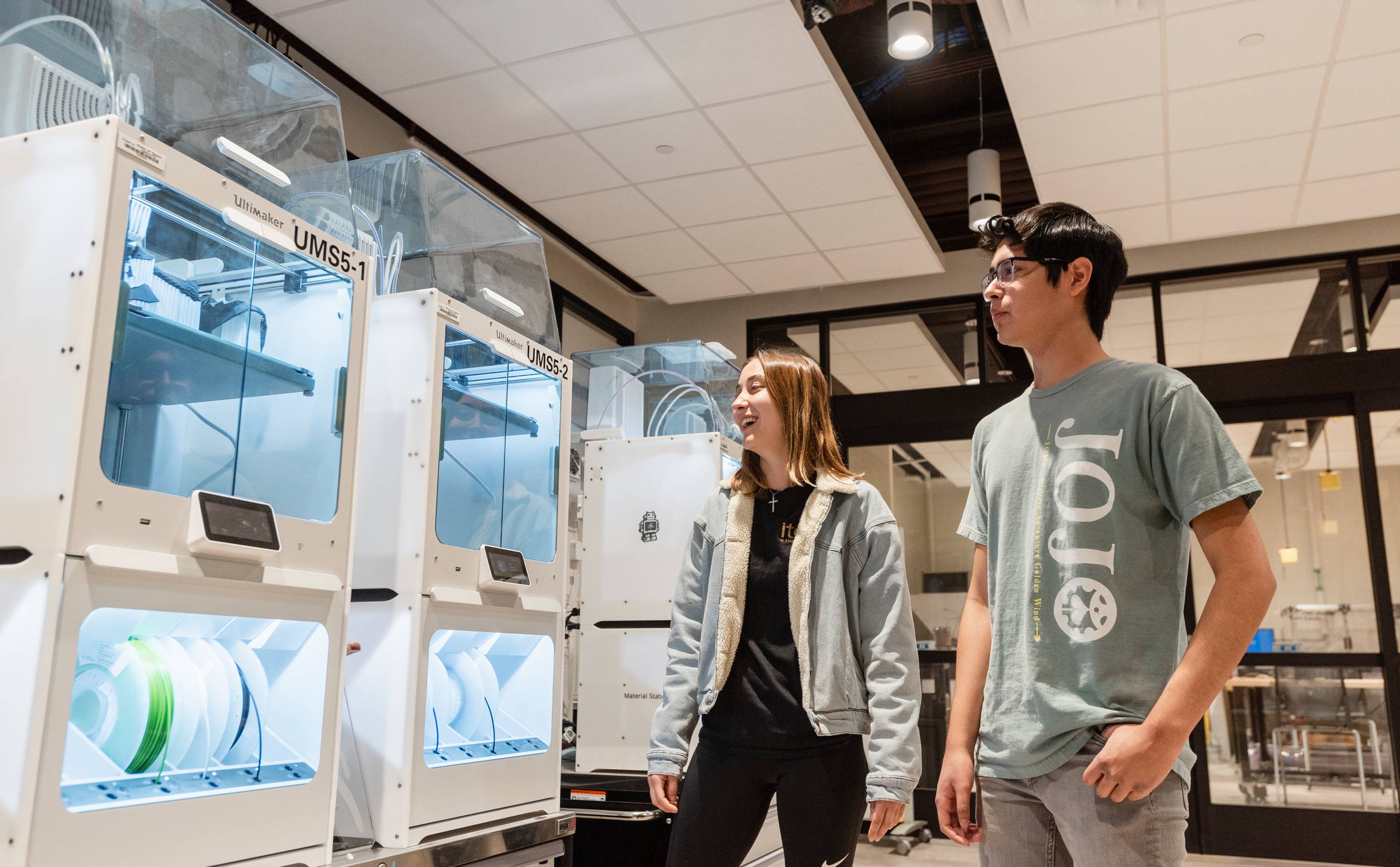 Students looking at row of 3D printers