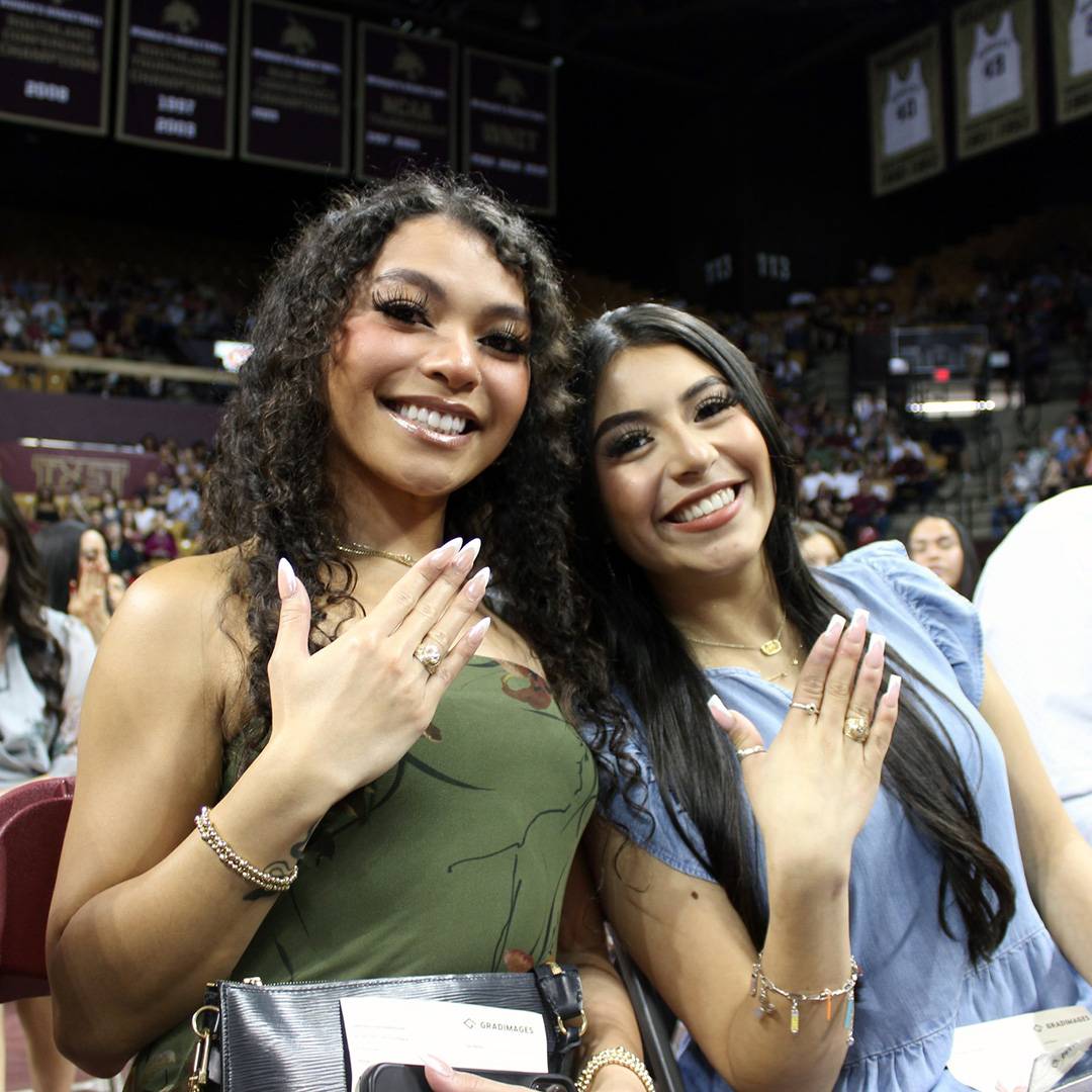 Two students holding up their hands wearing their class rings at the ring celebration