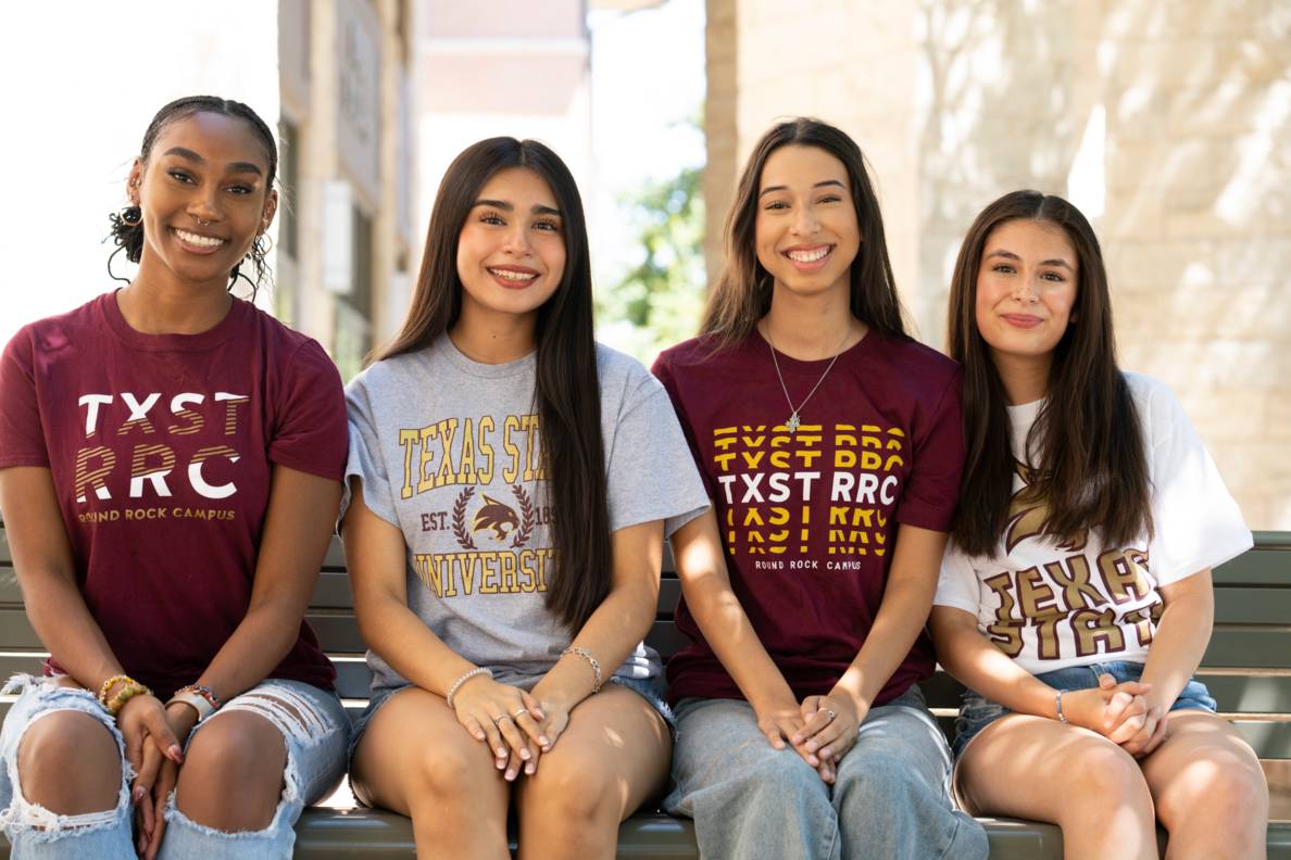 students sitting on a bench in txst gear