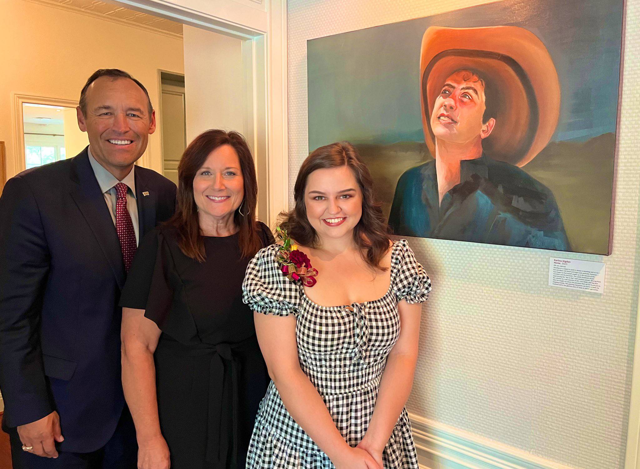 three people standing next to painting of man in cowboy hat