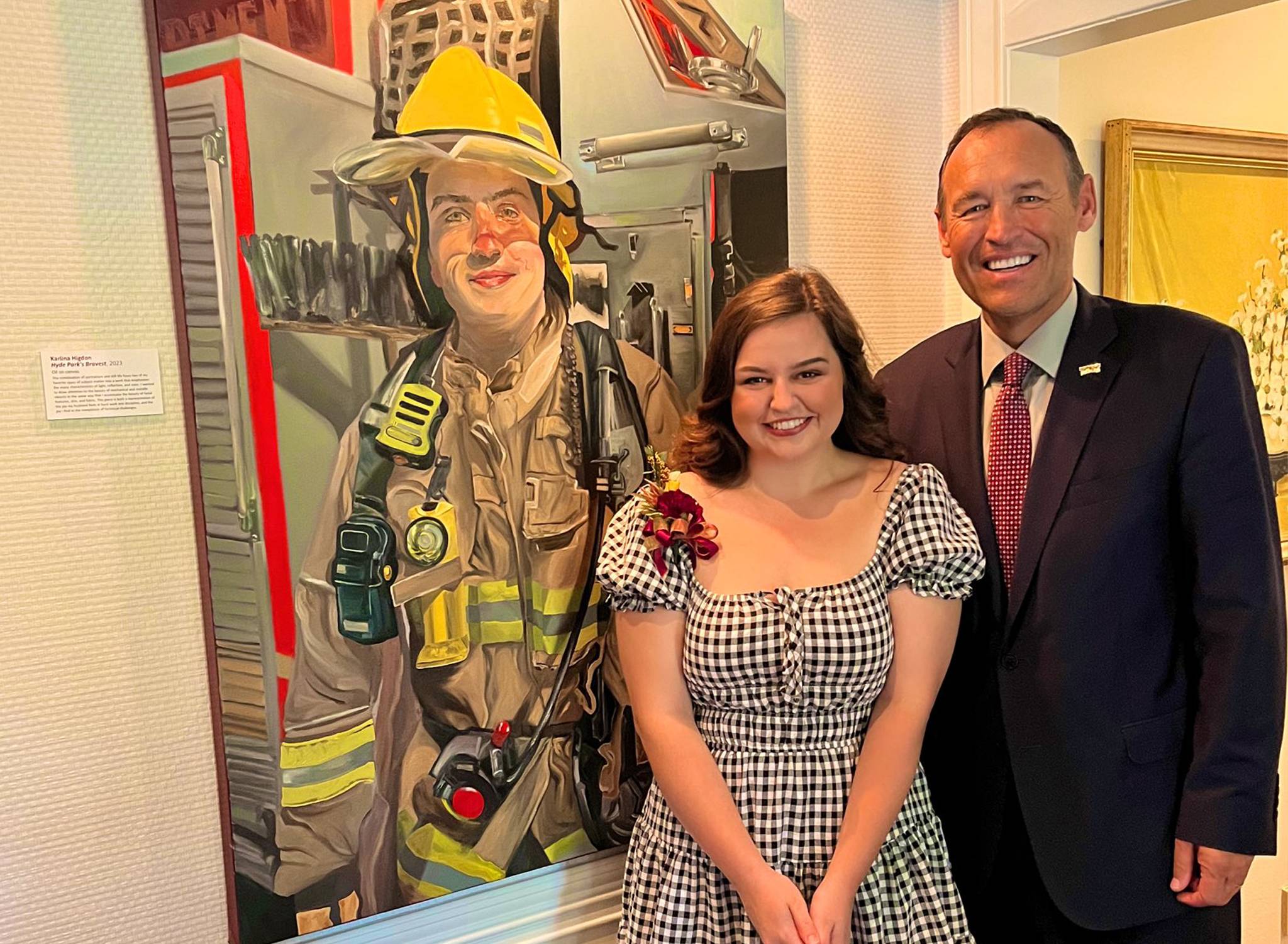 two people standing next to painting of firefighter