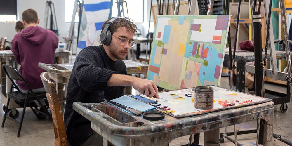 male art student painting in a studio