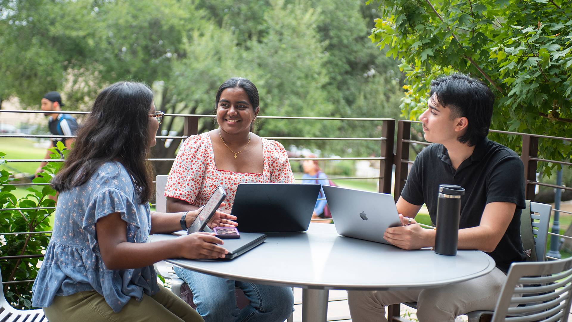 Three students at a table studying on the Texas State campus