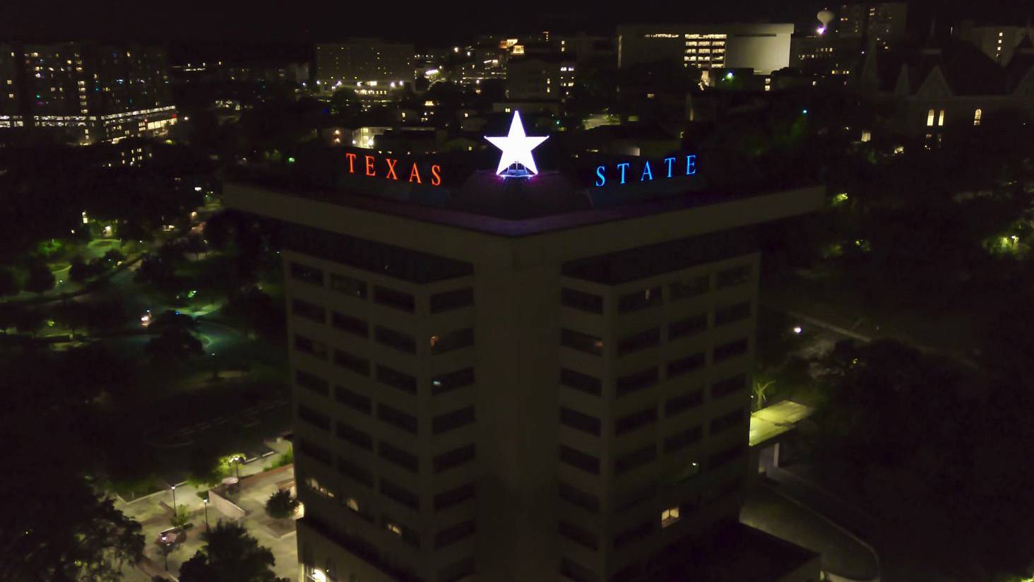 New Texas State letters and the Victory star are lit up atop JCK at night.