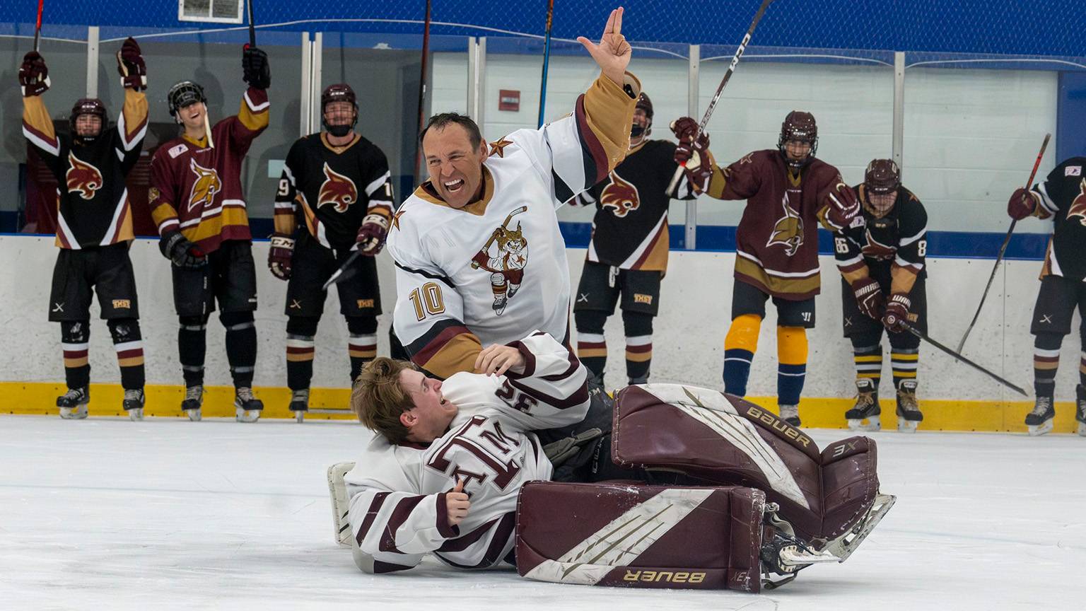 President Damphousse (middle) talks with members of the TXST Hockey team on the ice.