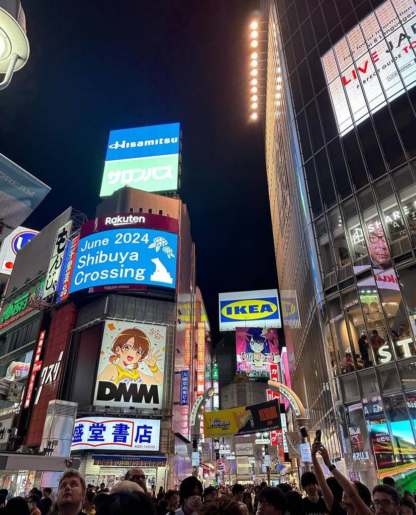 buildings lit up at night at shibuya crossing japan