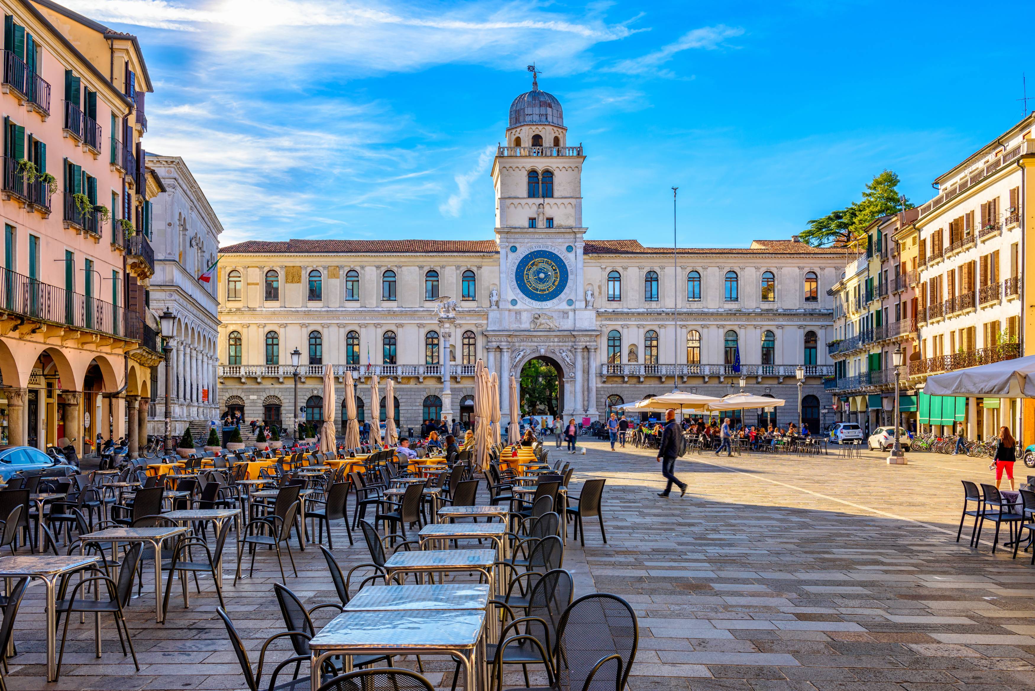 View of plaza and outdoor dining in front of Torre dell'Orologio (the clock house), featuring pedestrian-friendly walkways."