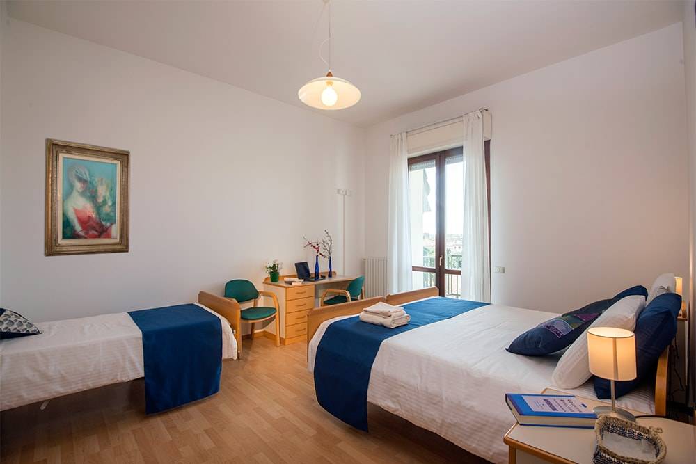 view of two beds, study desk, and doorway to balcony at Casa Al Carmine bedroom.