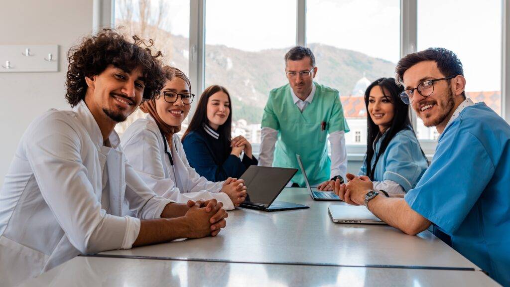 A group of physicians smiling while sitting at along table.