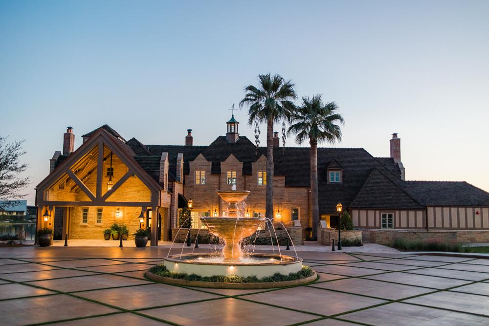 An image of the event venue, which is a large house with a fountain and paved driveway.