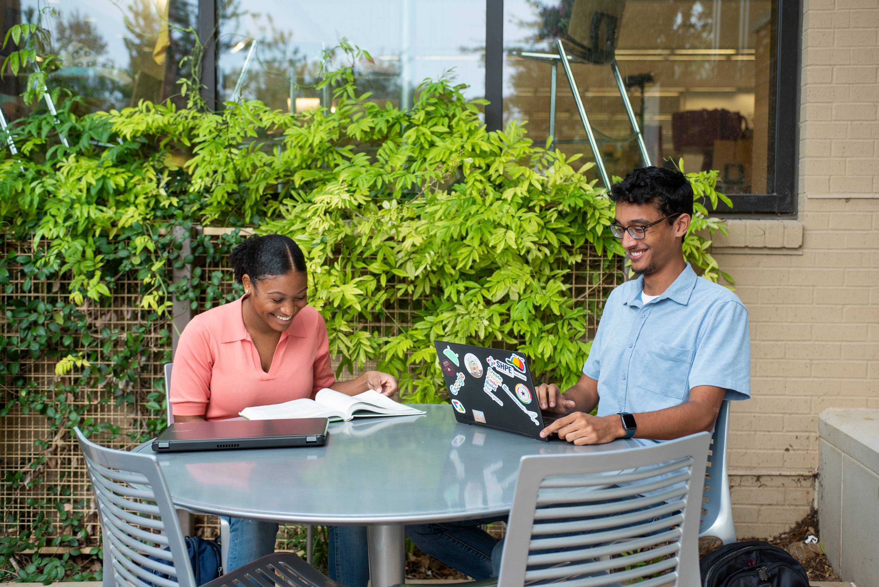 Two students sitting outside on a computer at Jones