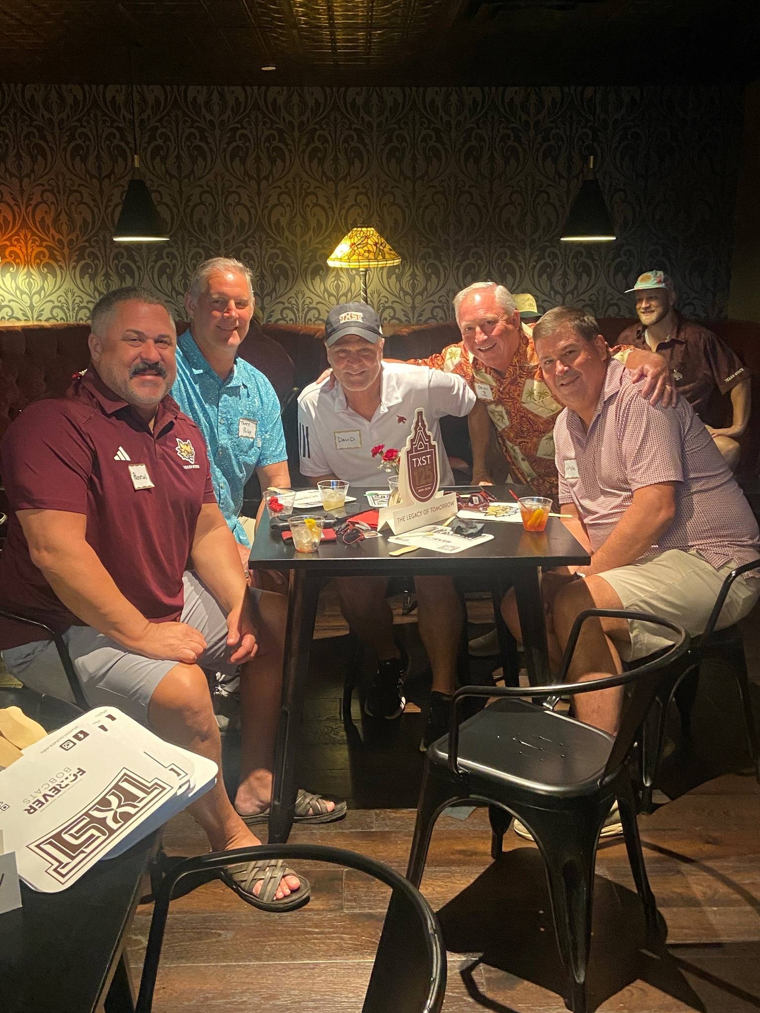 Group of Texas State fans sitting at a table during a watch party