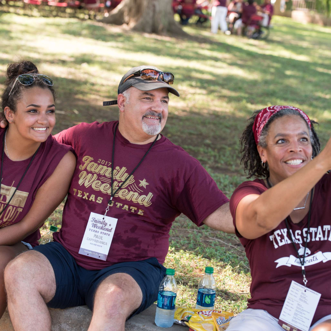 Two TXST parents with their student at Family Weekend taking a selfie. Links to: family weekend schedule