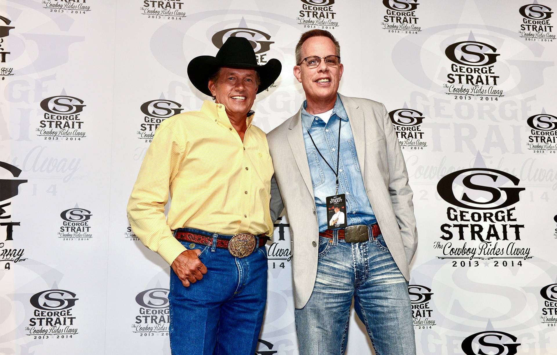 two people pose for a photo in front of an event backdrop