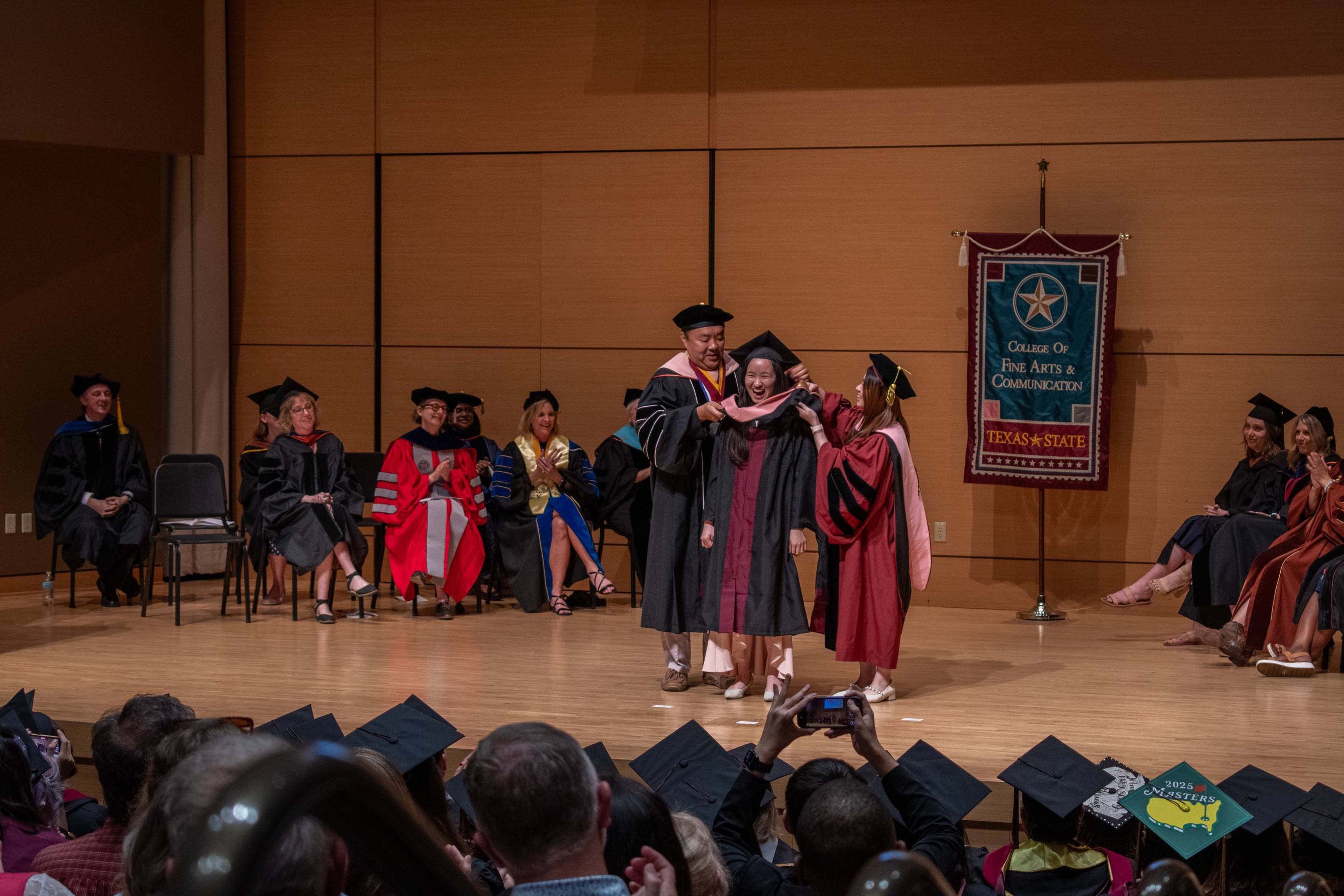 A Masters Hooding Ceremony recipient on stage
