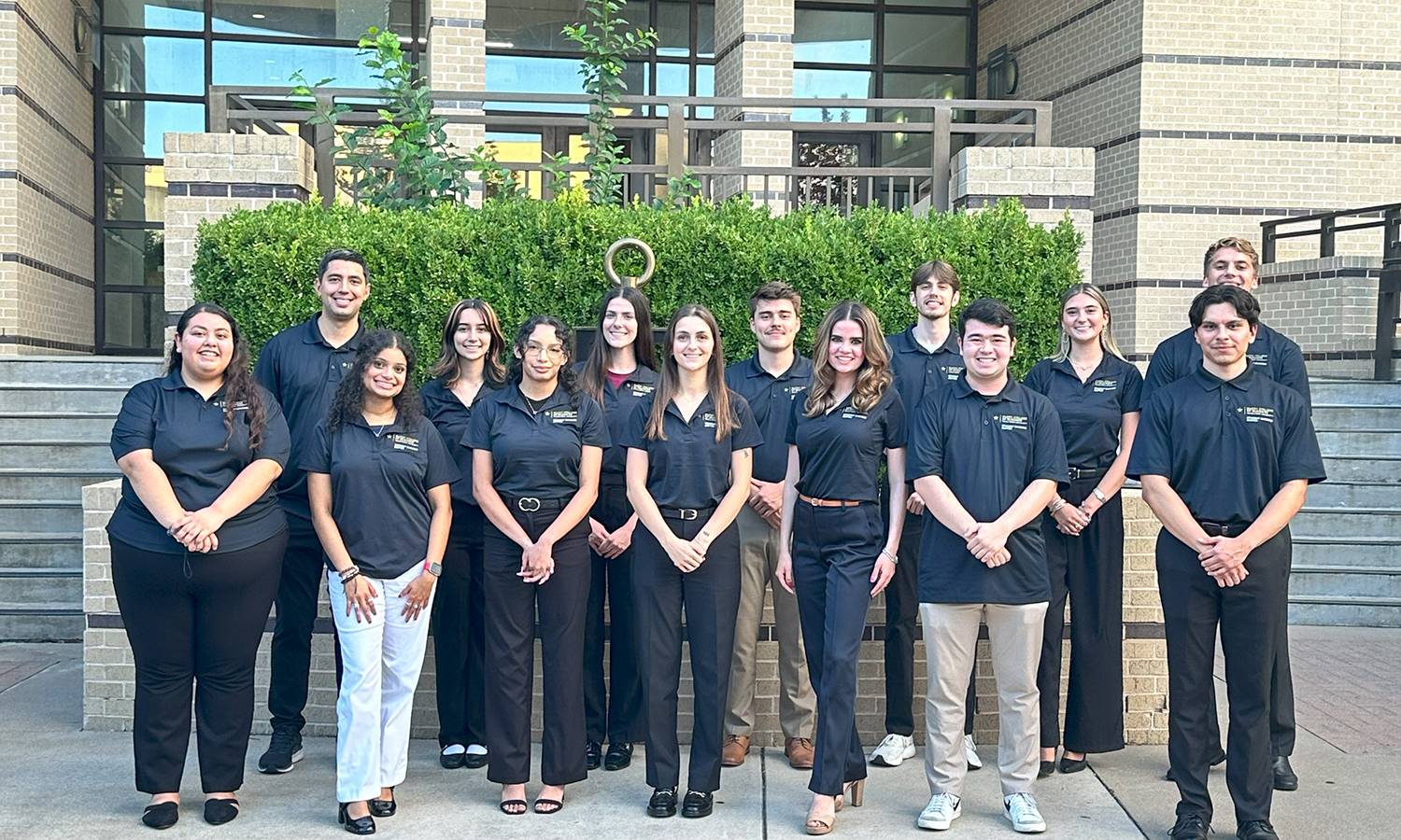 Student Success Ambassadors members standing in front of the Beta Gamma Sigma symbol outside of McCoy College of Business