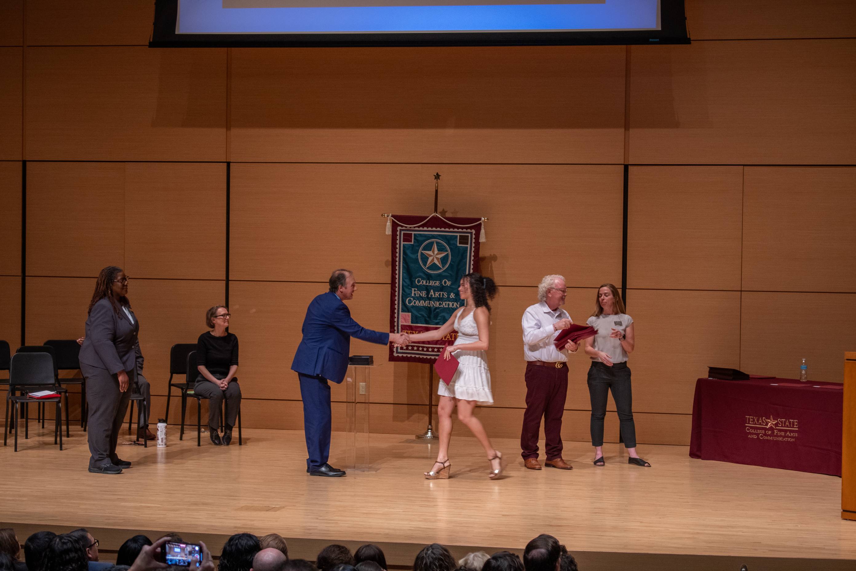 a student shaking the deans hand at the council of scholars ceremony 