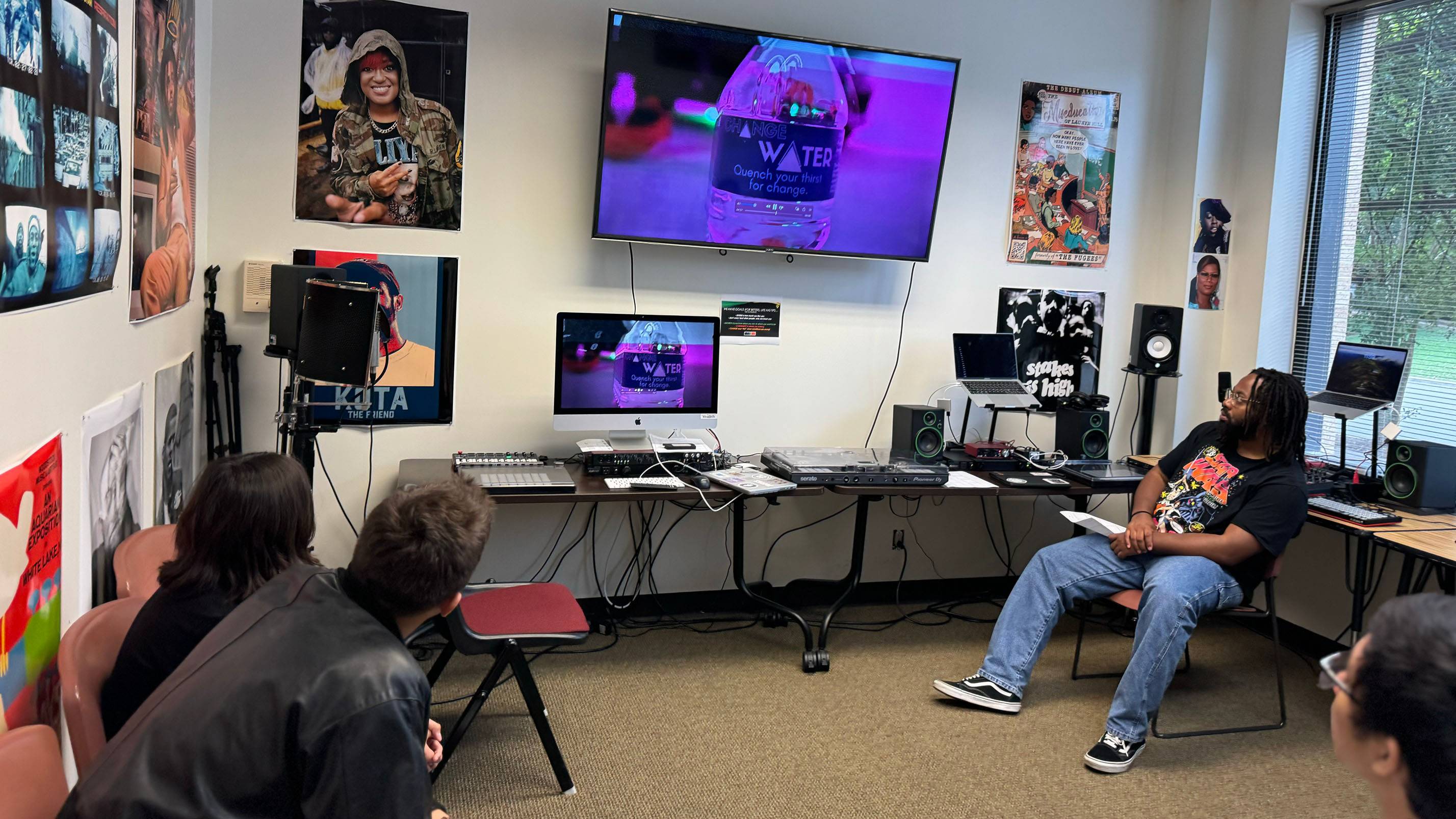 A teacher and students watch a video they created during a camp.