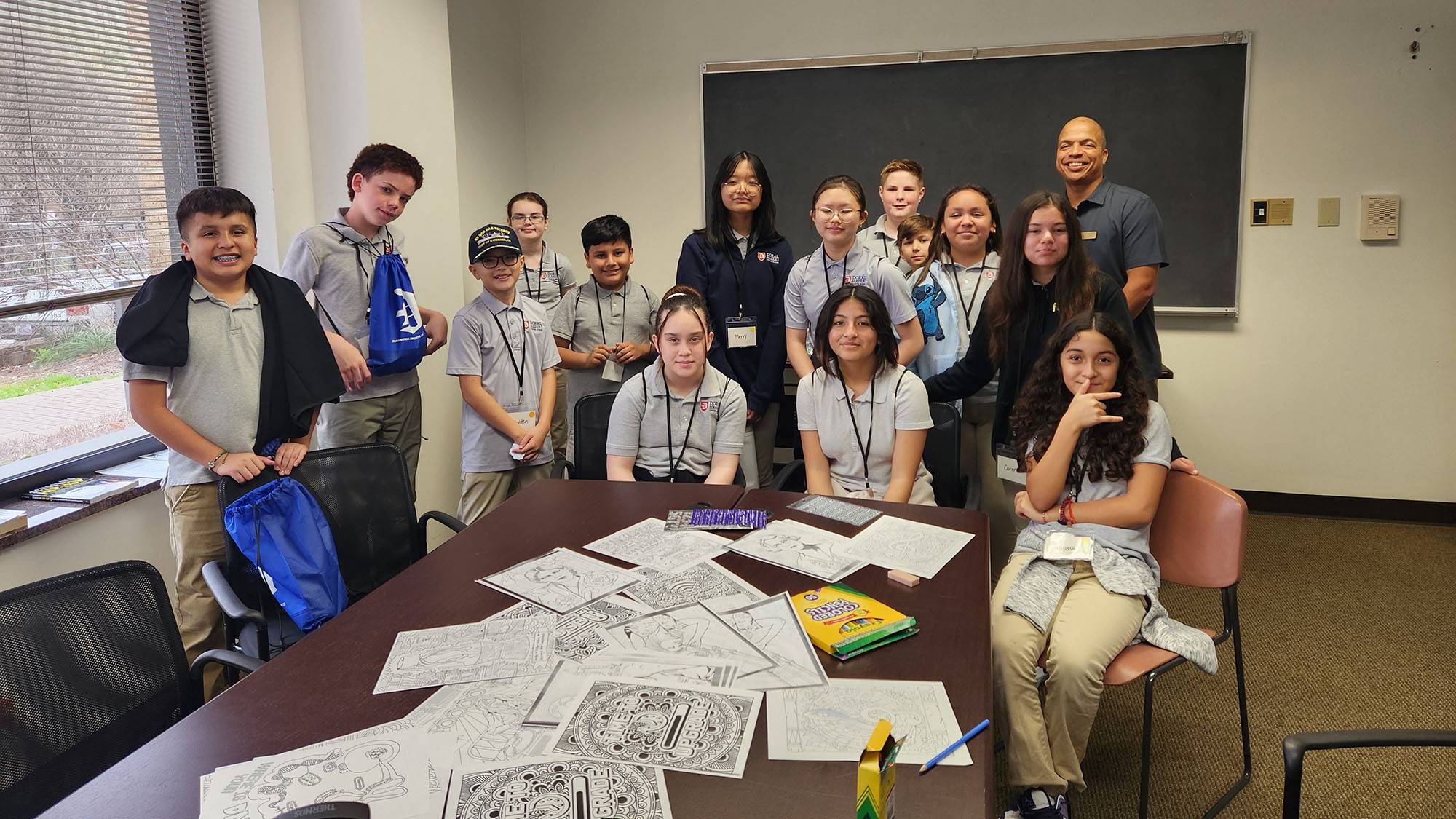 A group of students and Raphael Travis (right) pose for a photo in a classroom during a camp.