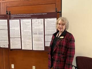 Ms. Lori Stiriz standing next to her research poster.