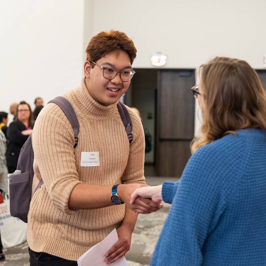 Student shaking hands with an employer at a Texas State career fair 