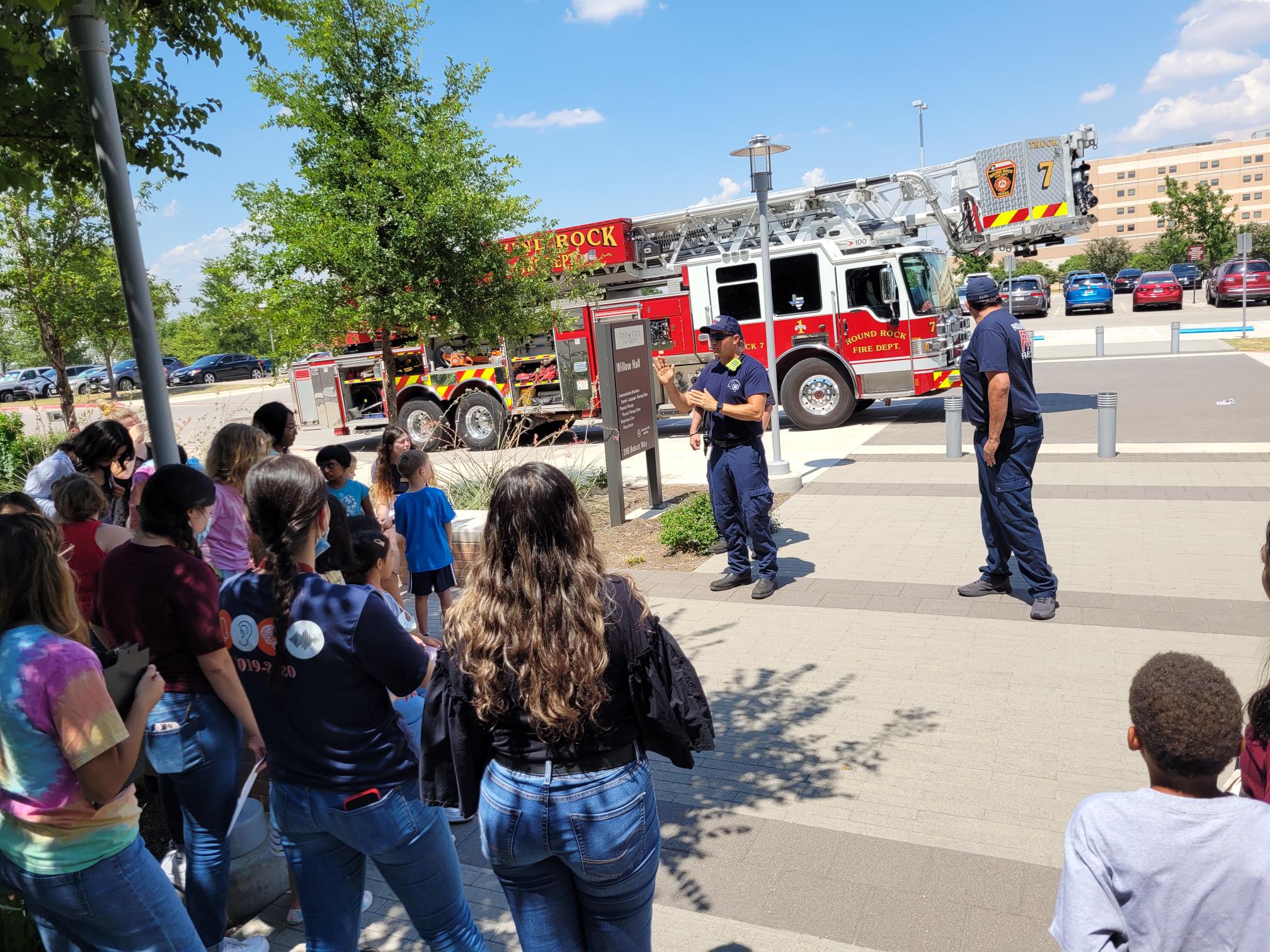 Firefighters showing young patients their firefighter's truck.