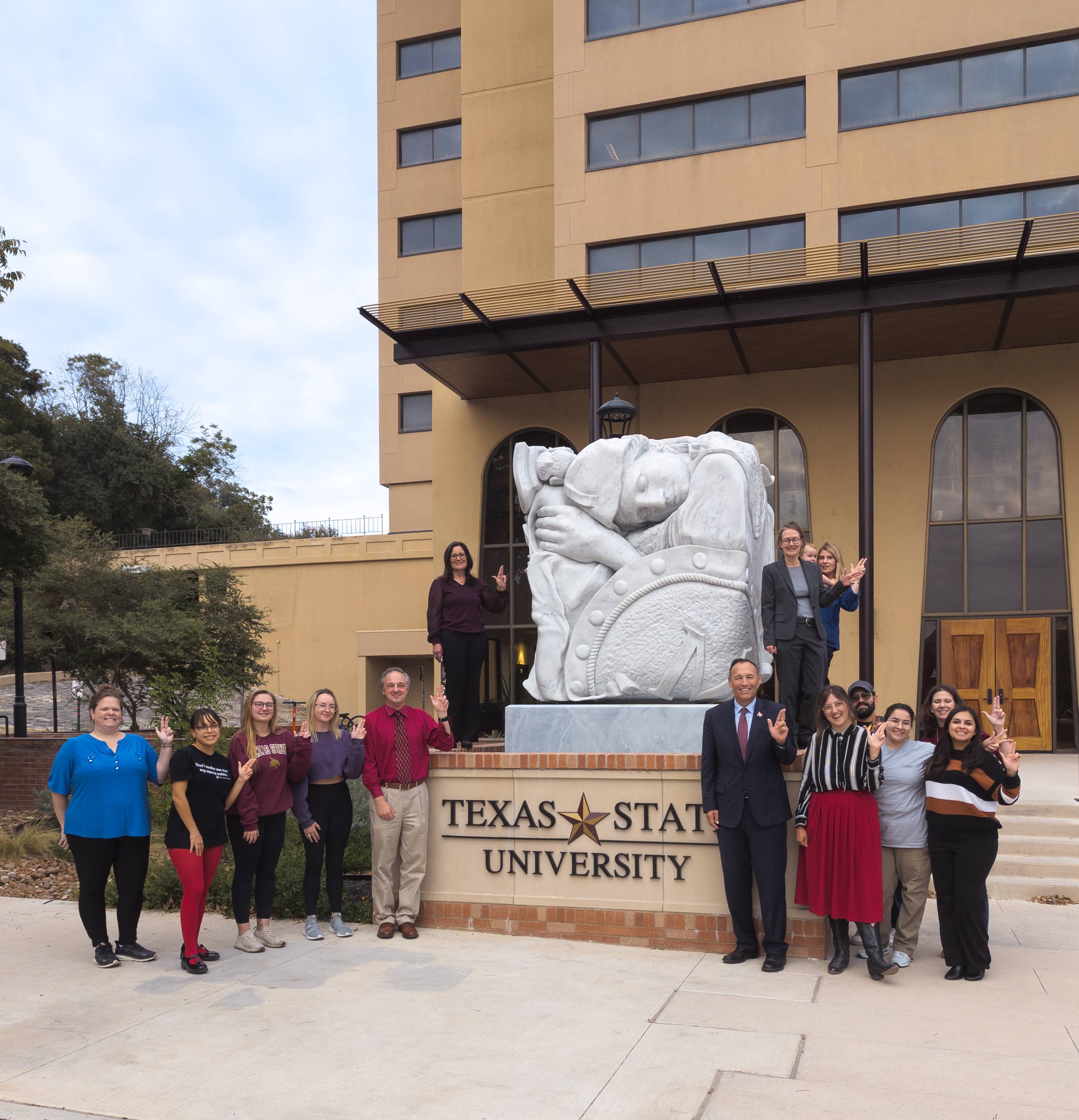 group posing for photo in front of cubed marble sculpture