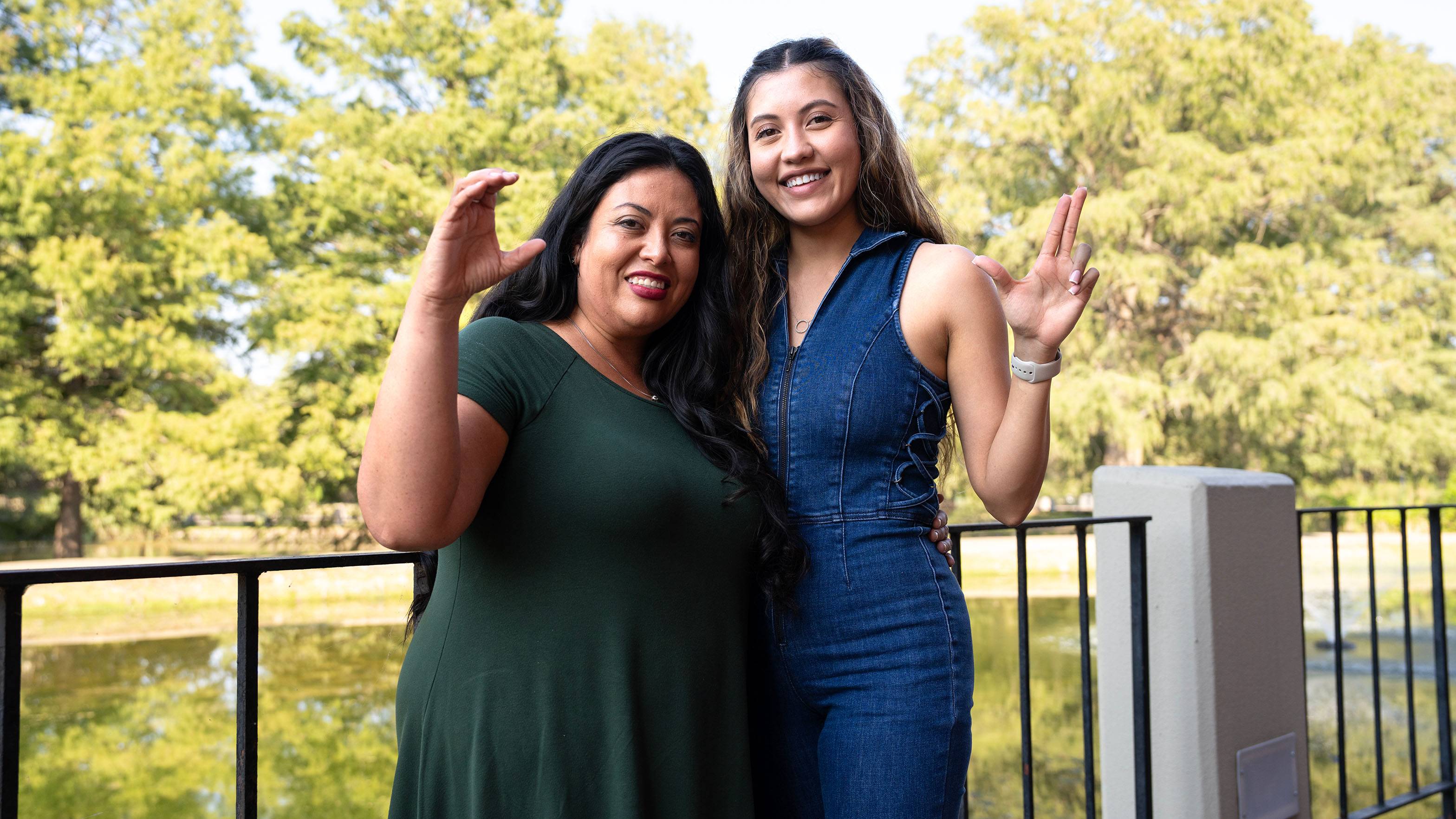 Valerie (left) and Abigail Pena pose for a photo together outside in front of a pond.