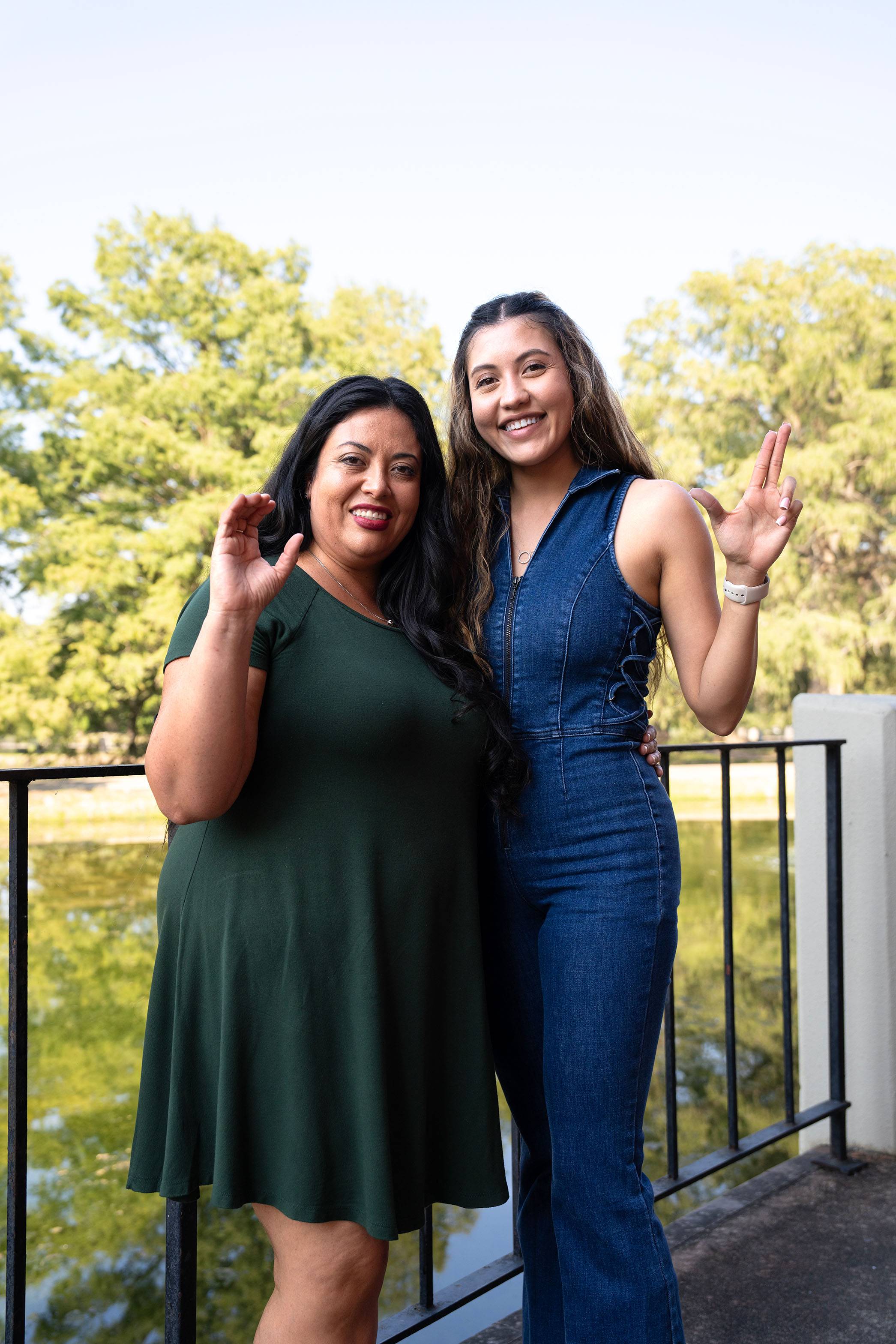 Valerie (left) and Abigail Pena pose for a photo together outside in front of a pond.