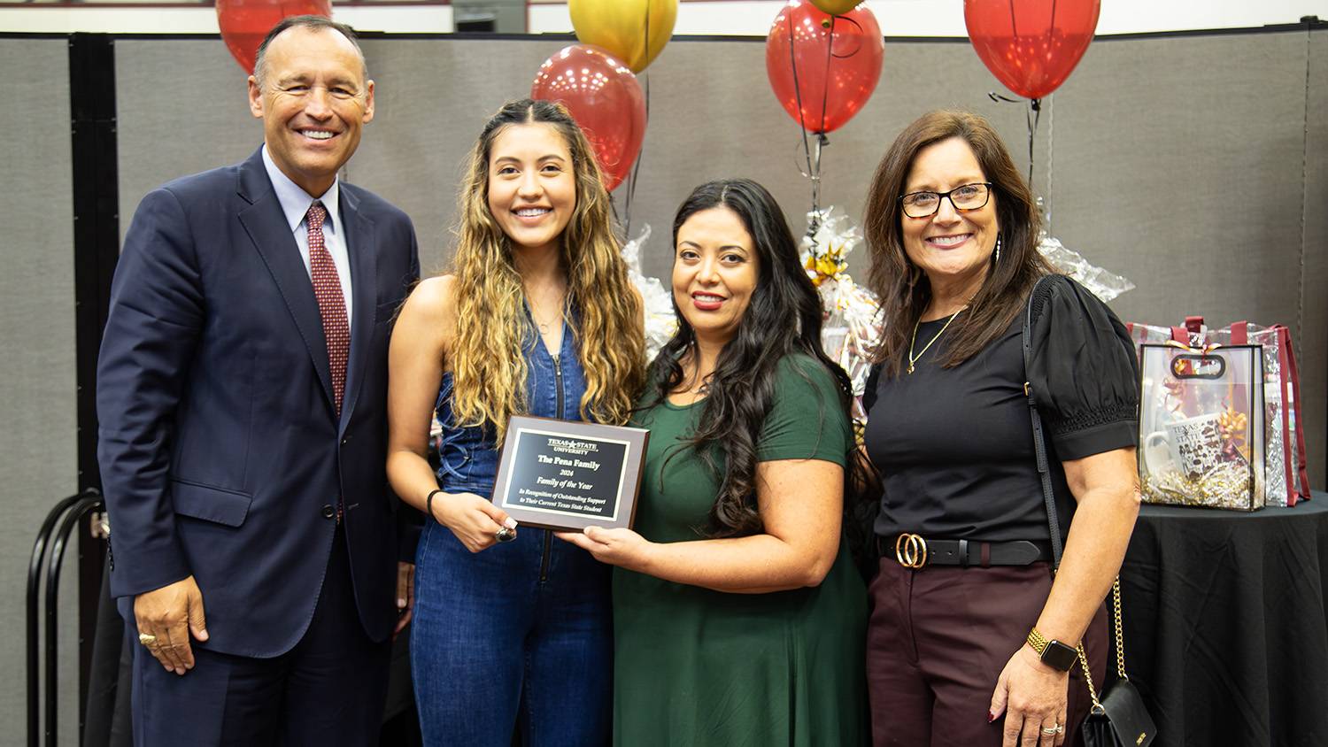 President Kelly Damphousse (left) poses for a photo with Abigail and Valeria Pena and First Lady Beth Damphousse with the Family of the Year plaque.