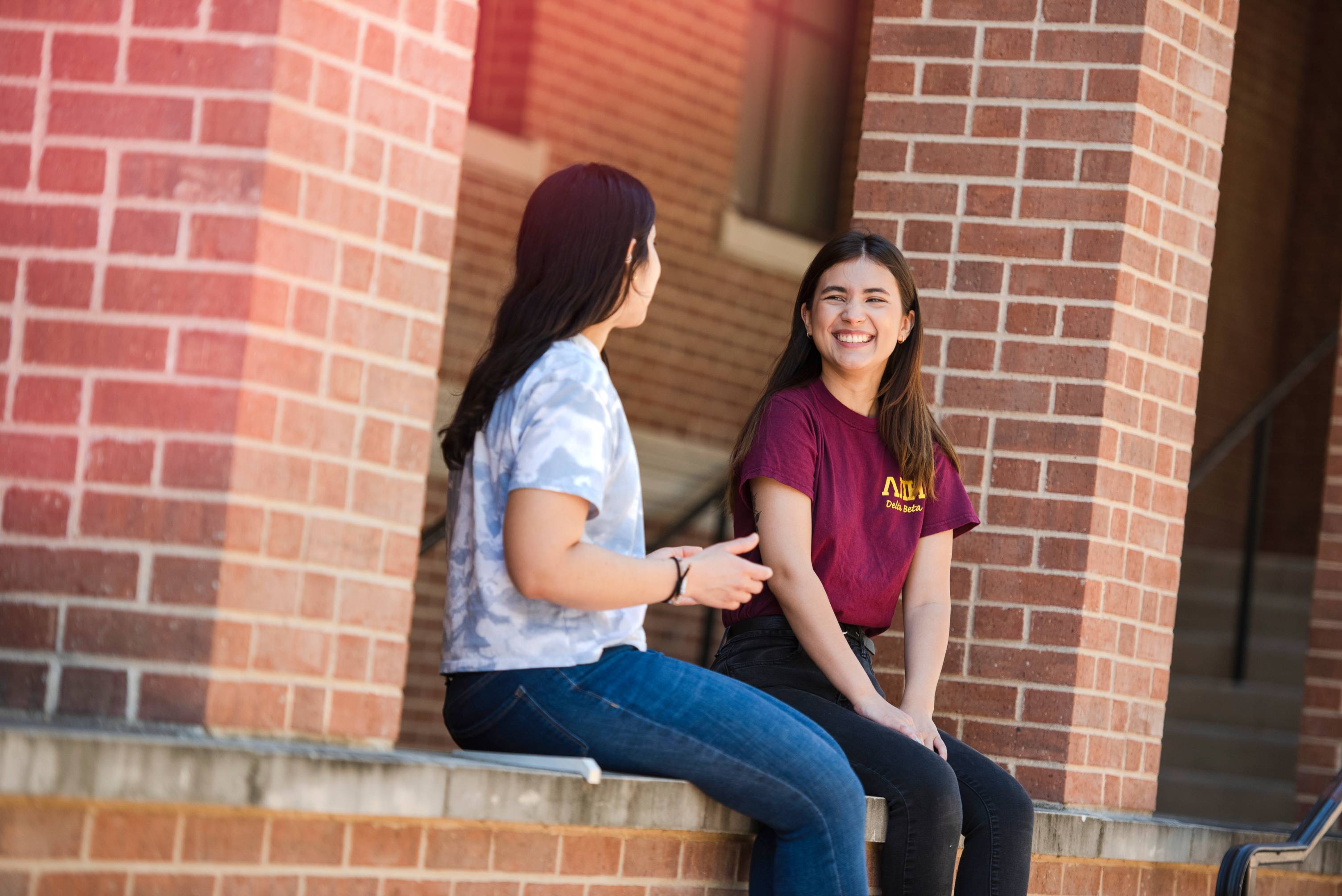 two students sitting outside chatting