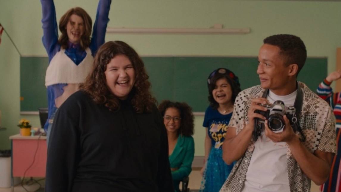 Mia Kaplan (left) smiles with a group of students in a scene from the movie Empire Waist.