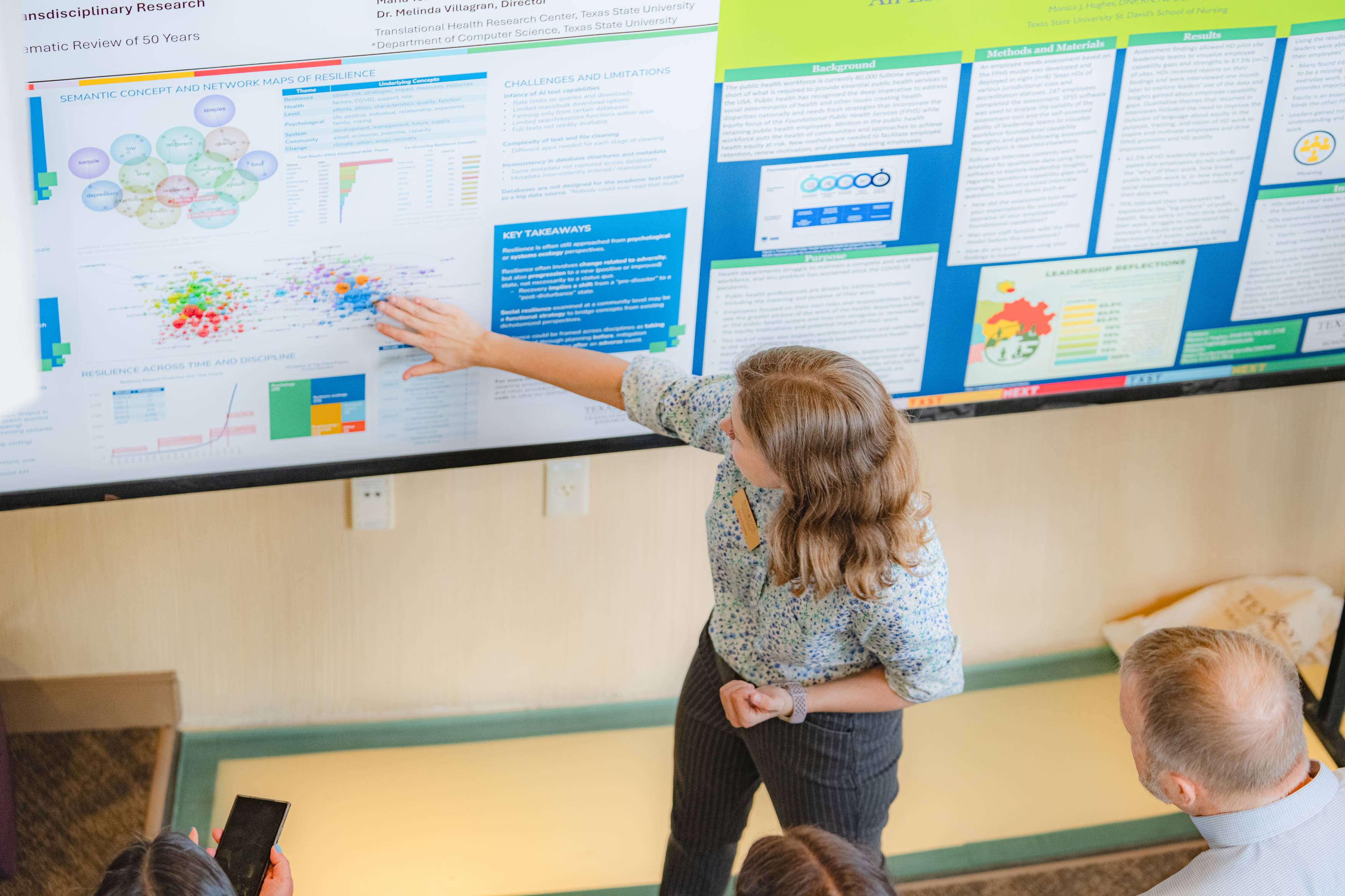 A view of the first and second story balcony from inside the Health Scholar Showcase venue. On the balconies, health research posters are displayed and attendees are walking around viewing them. 