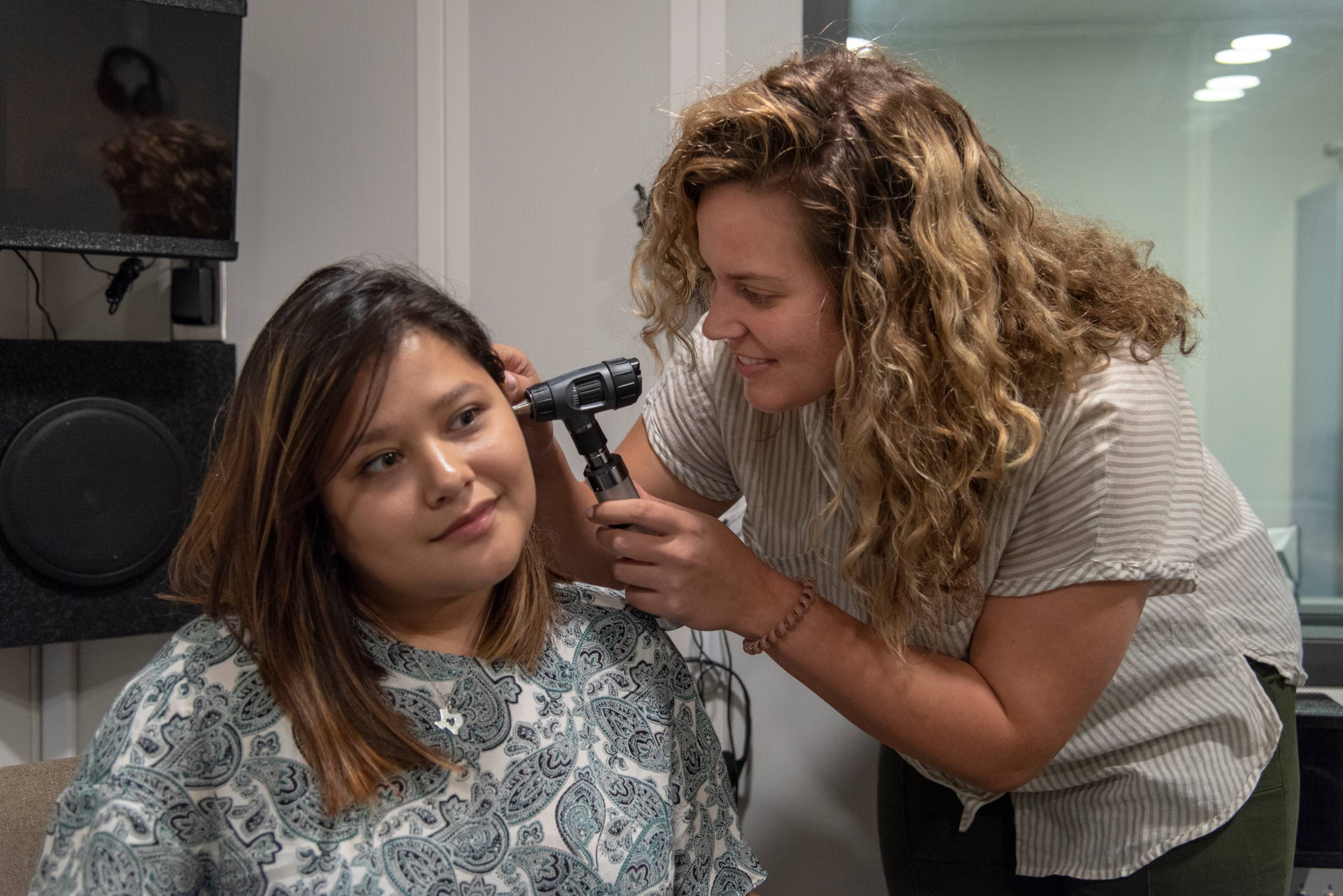 Student clinician examining patient's ear.